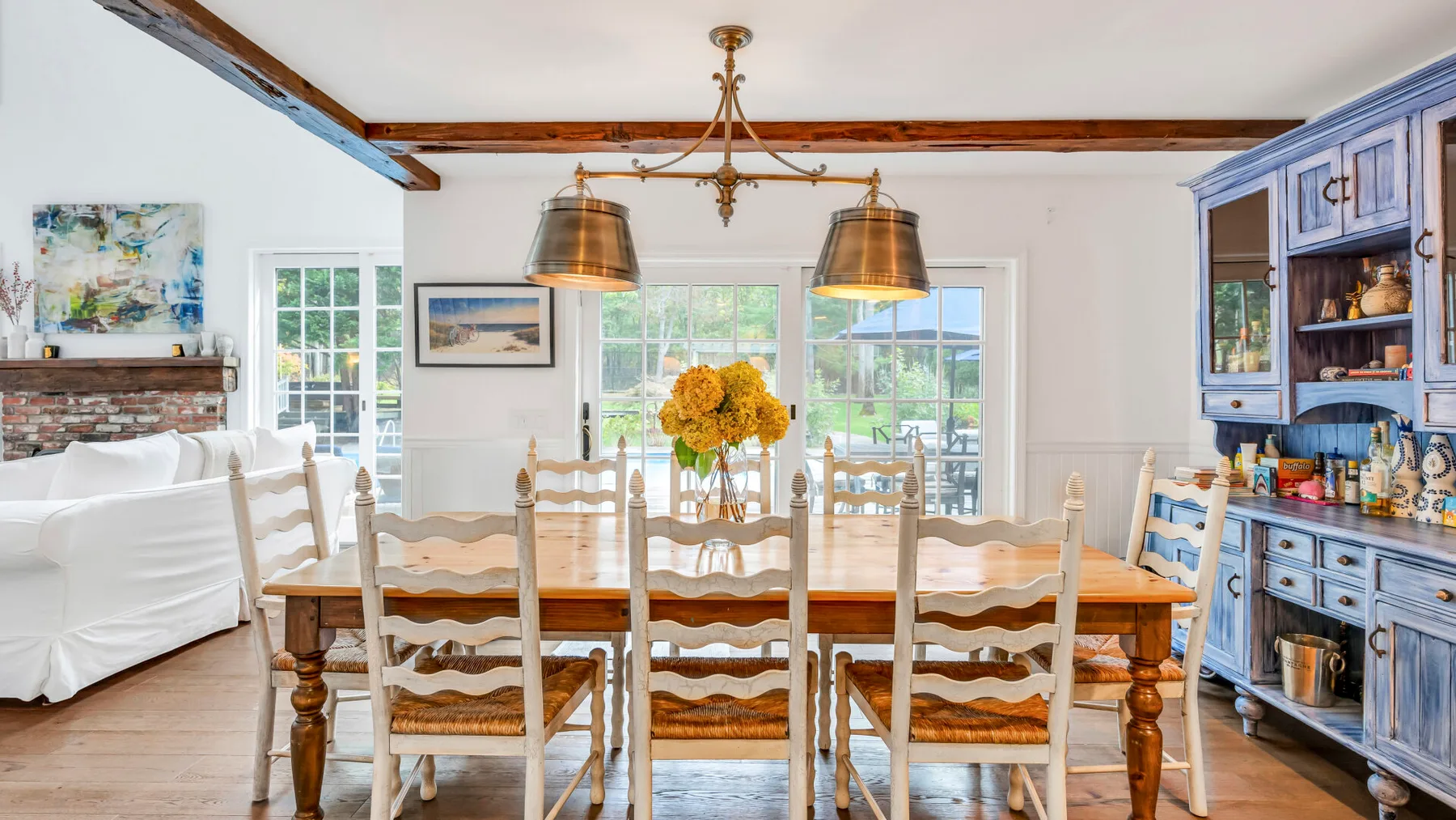 Un comedor luminoso tiene una larga mesa de madera, sillas y un armario azul.