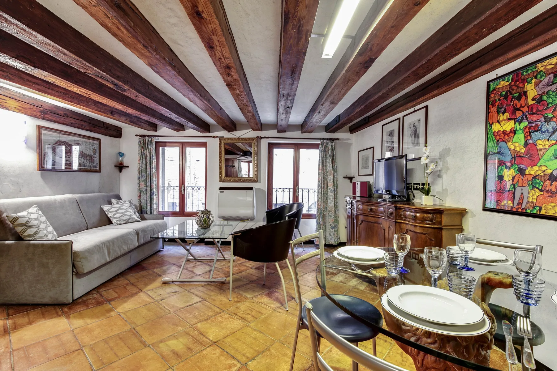 Una sala de estar y comedor con vigas expuestas y una mesa puesta.