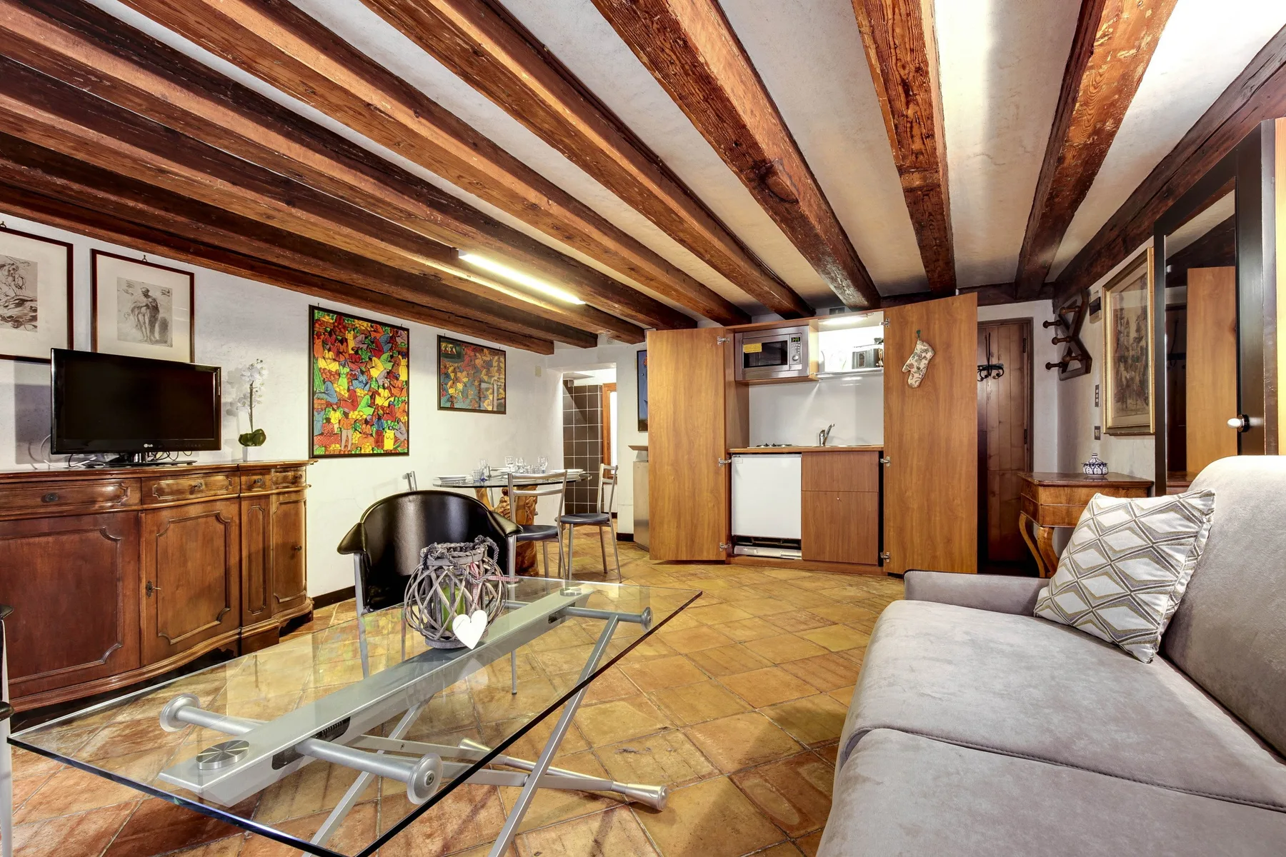 Una sala de estar con vigas de madera a la vista y una mesa de centro de vidrio.