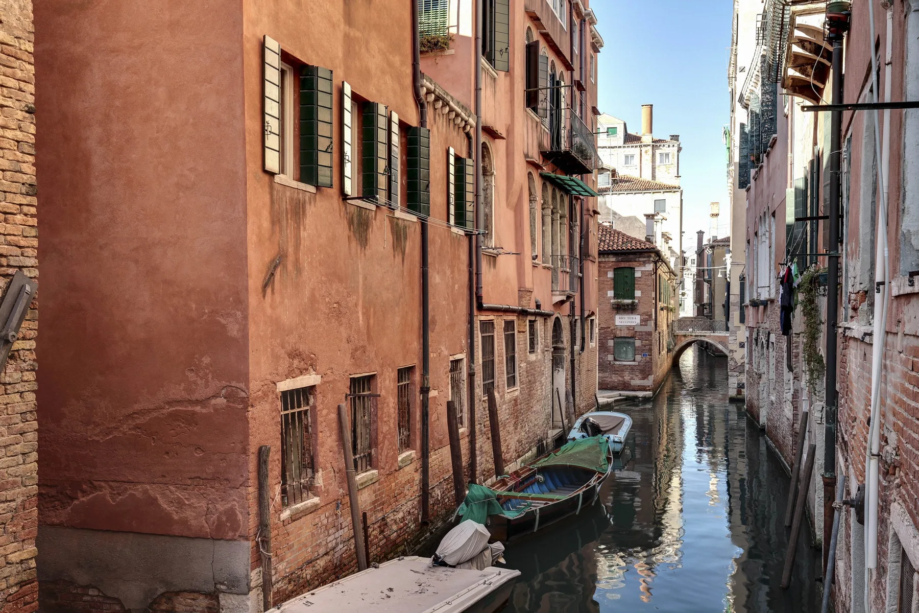 Un canal estrecho pasa entre edificios cercanos, con varias embarcaciones junto al agua.