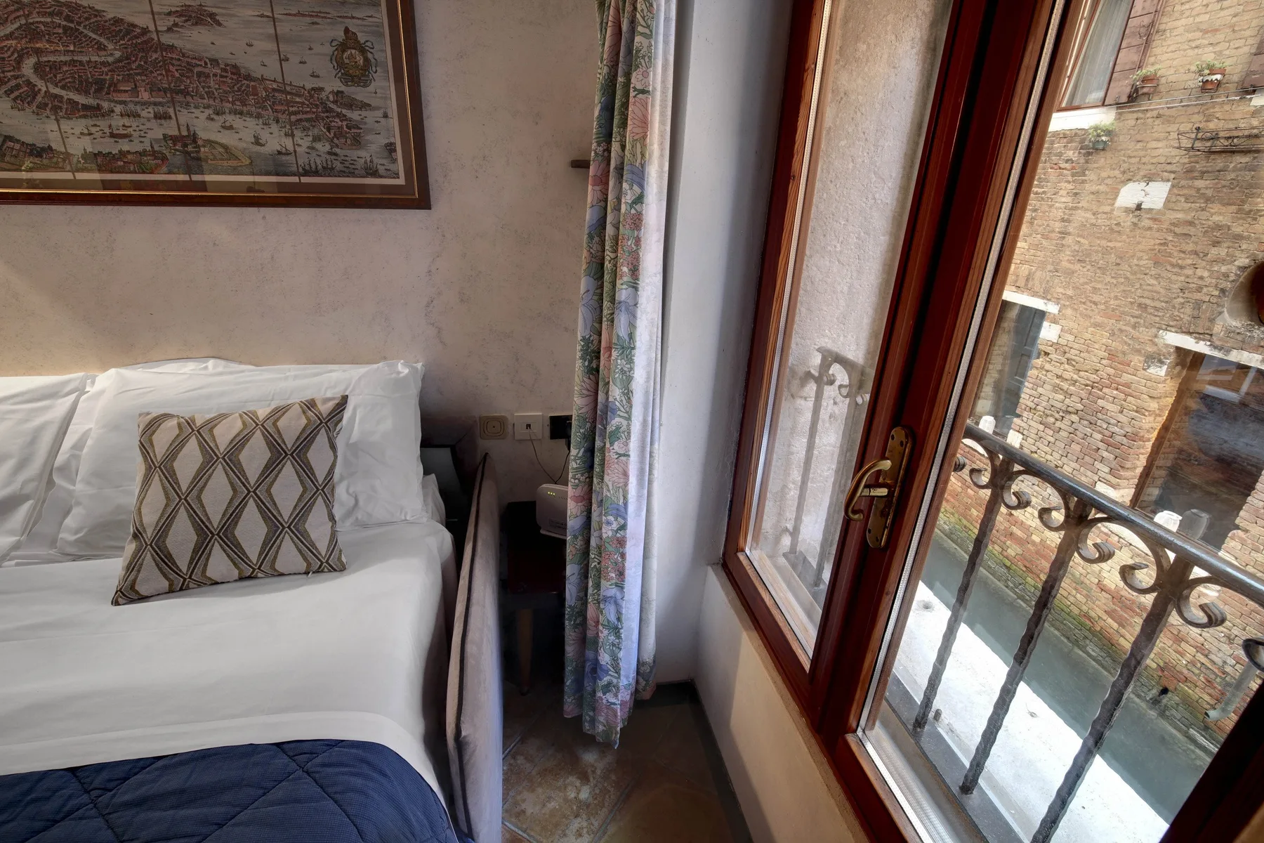 Un dormitorio con una cama bien tendida junto a una ventana alta.