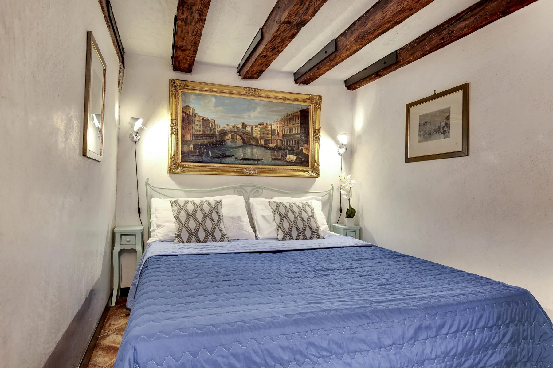 Un dormitorio con una cama bajo vigas expuestas y cuadros enmarcados.