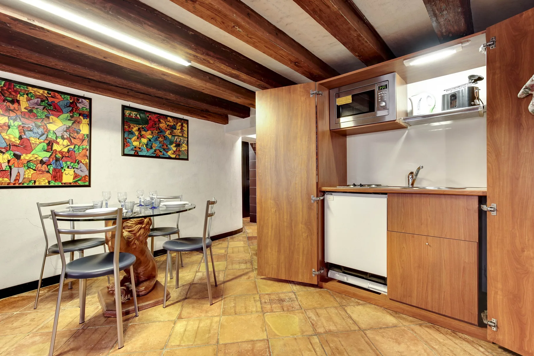 Una cocina compacta con zona de comedor, muebles de madera y una mesa.