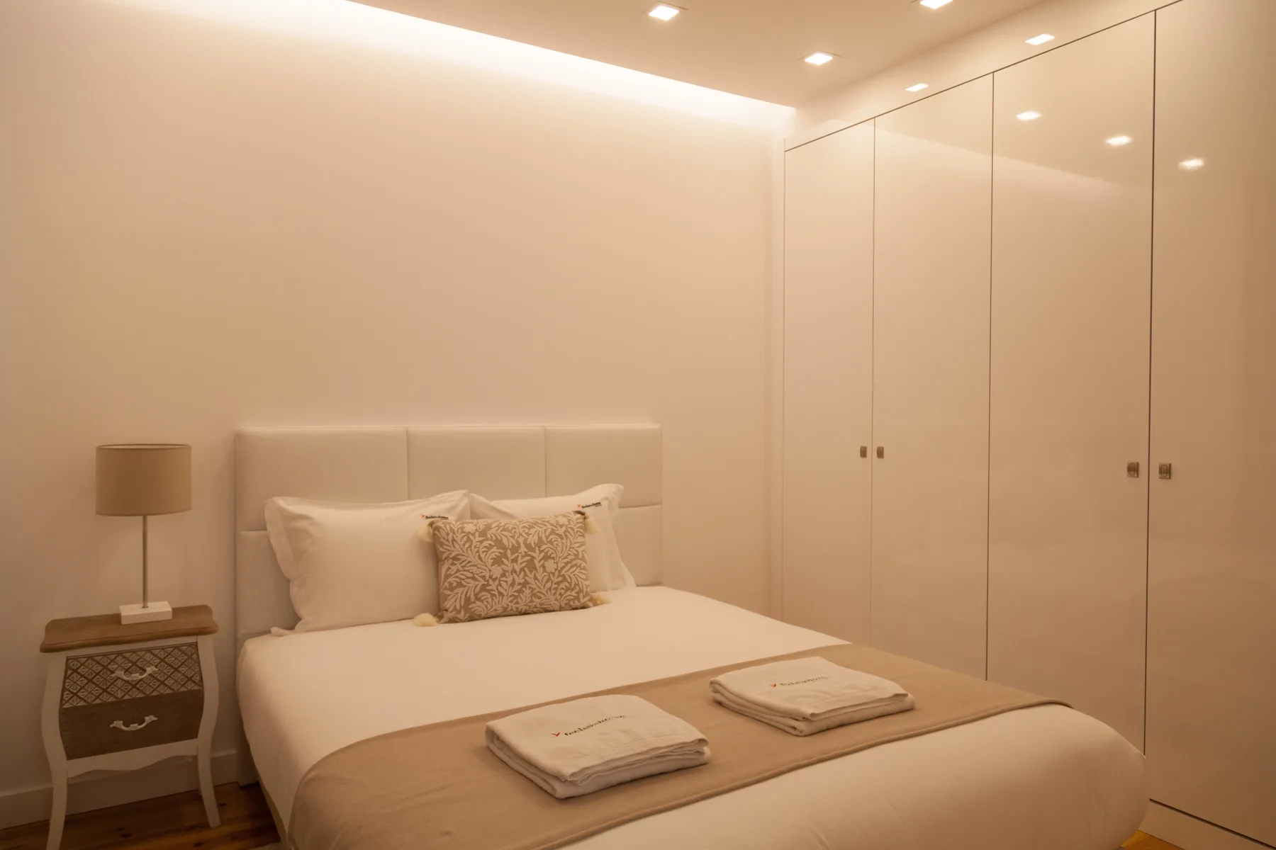 Un dormitorio con una cama bien arreglada y armarios empotrados.
