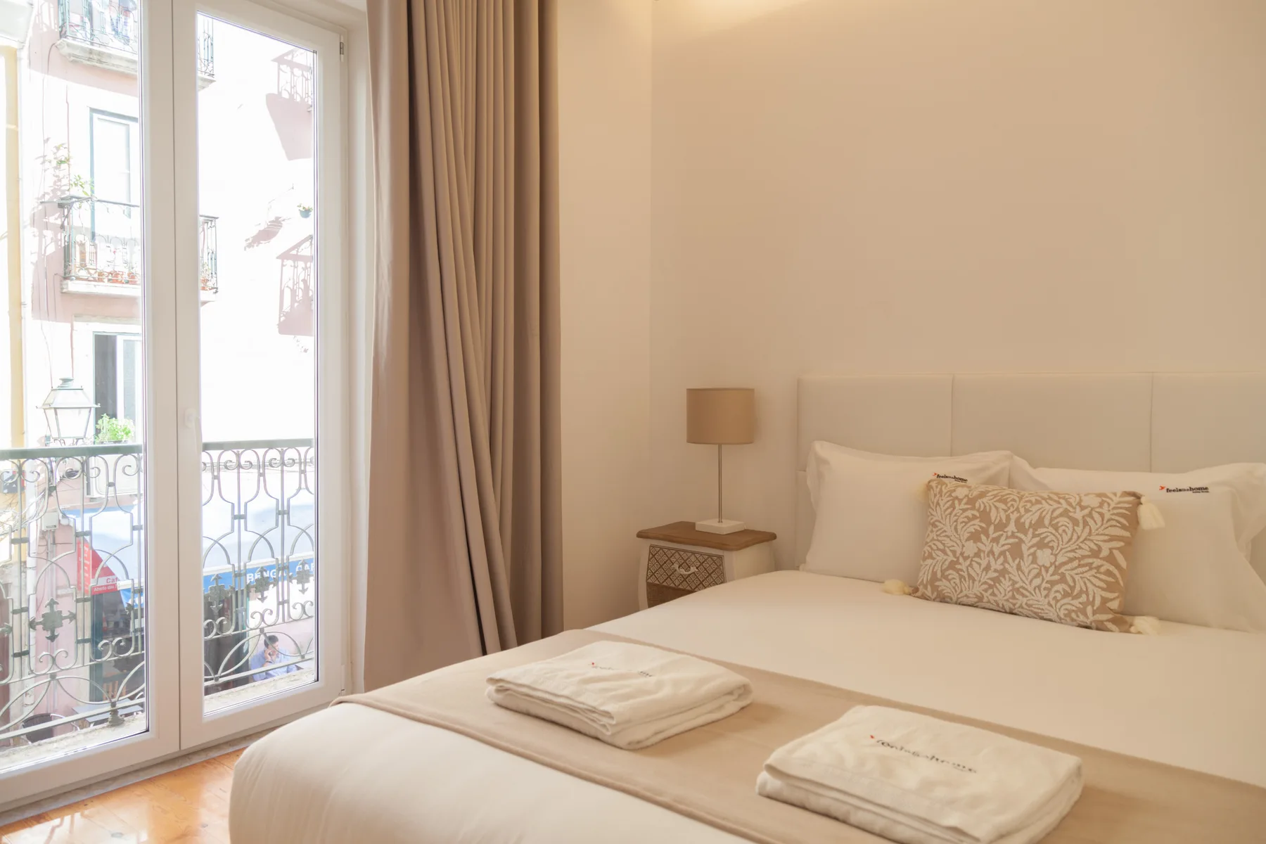 Un dormitorio luminoso con una cama bien hecha junto a una ventana alta.