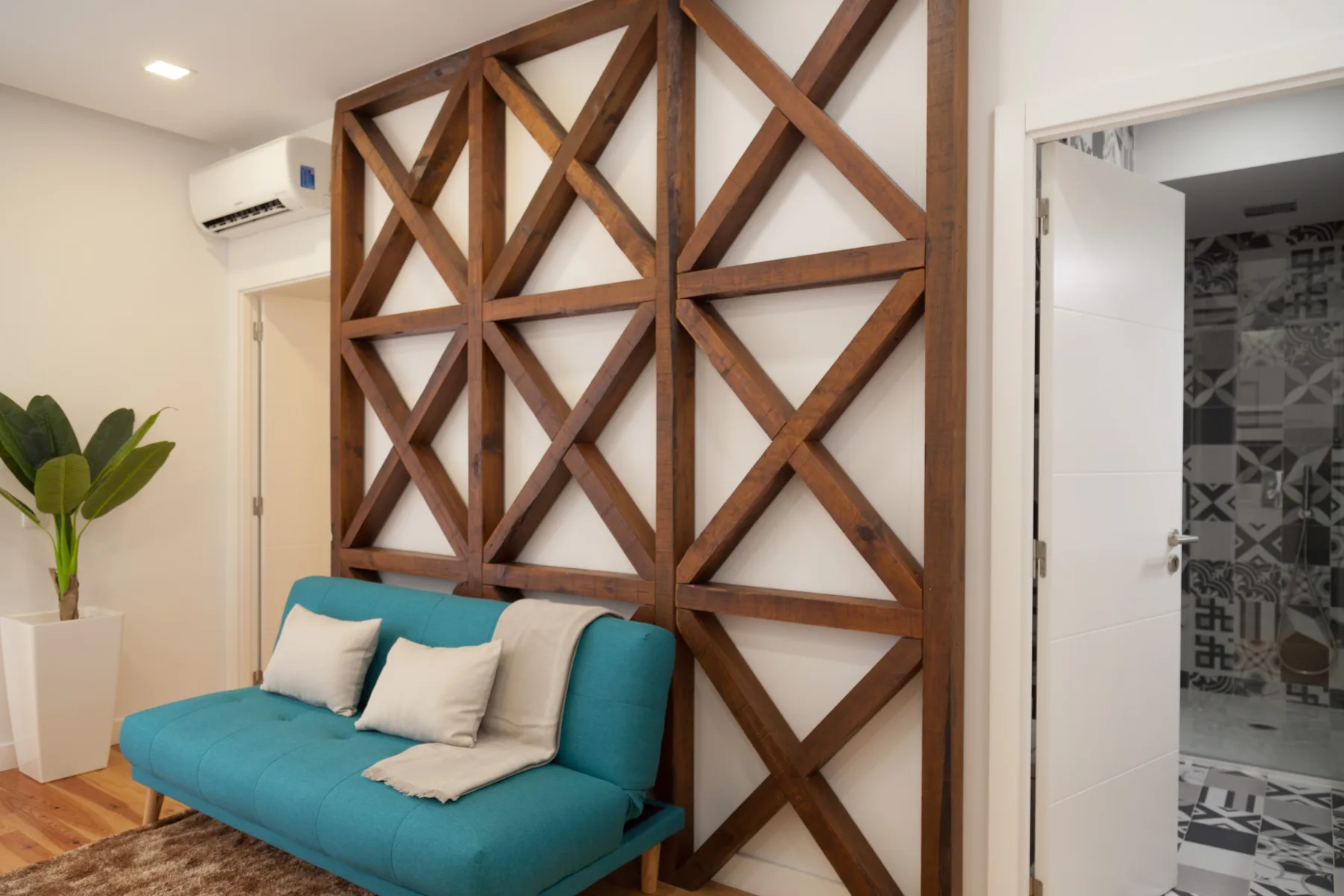 Una sala de estar con asientos turquesa junto a una celosía de madera y una puerta abierta.