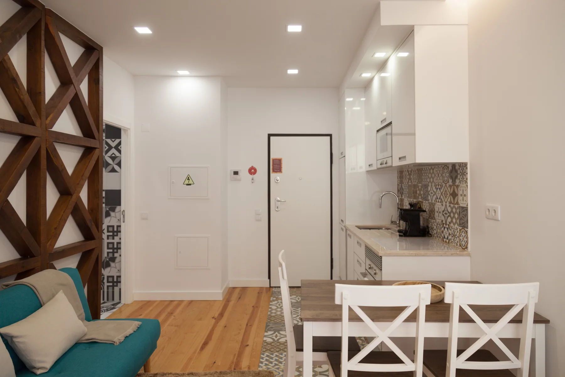 Una cocina y zona de comedor luminosa con un sofá verde azulado y suelo de madera.