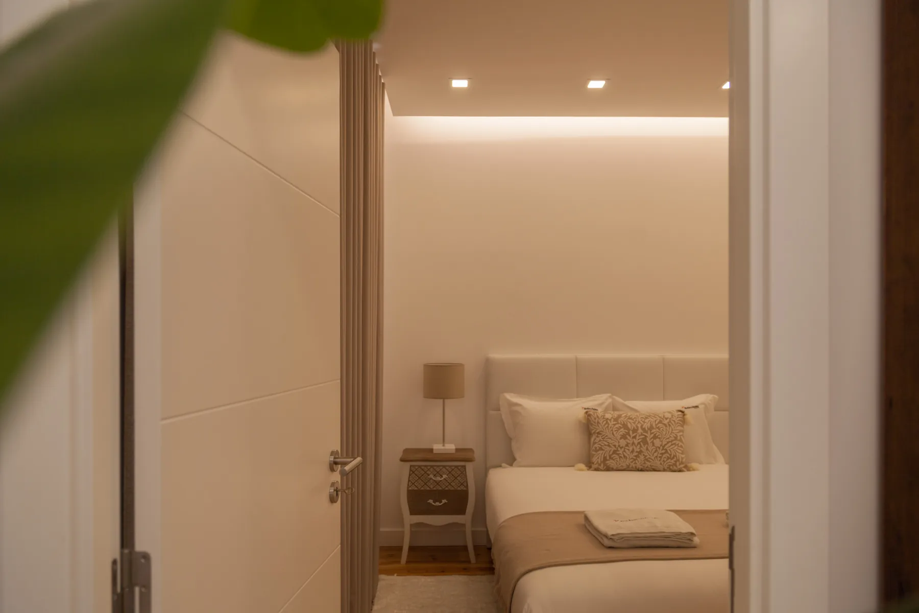 Un dormitorio con una cama bien hecha y una mesita de noche.