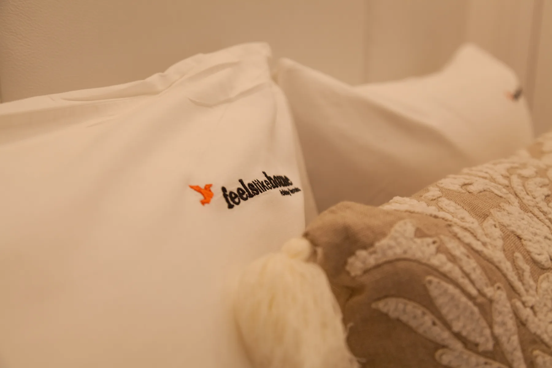 Una cama con almohadas blancas y una manta estampada.