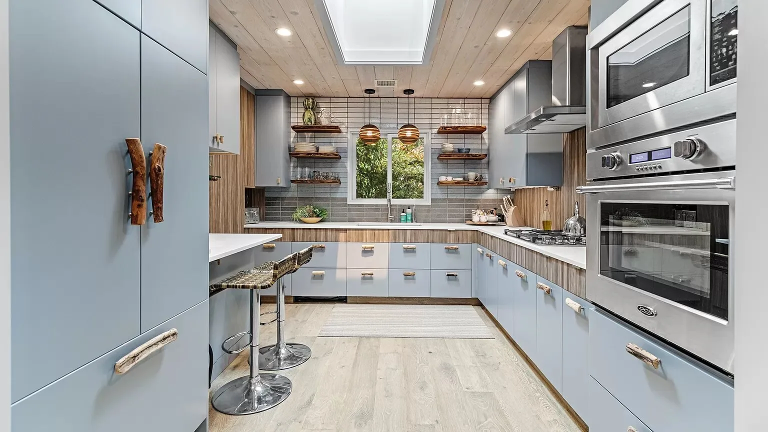 Una cocina moderna con armarios azules, una isla central y electrodomésticos de acero inoxidable.