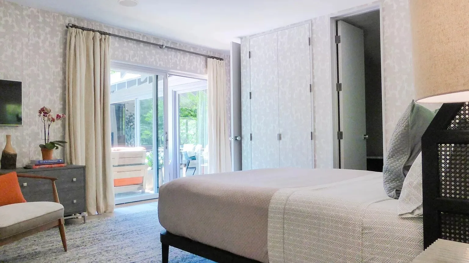 Un dormitorio con una cama grande junto a puertas corredizas de vidrio que dan a un balcón.