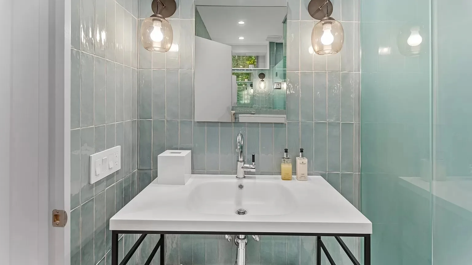 Un tocador de baño con azulejos, un lavabo blanco amplio y un espejo.