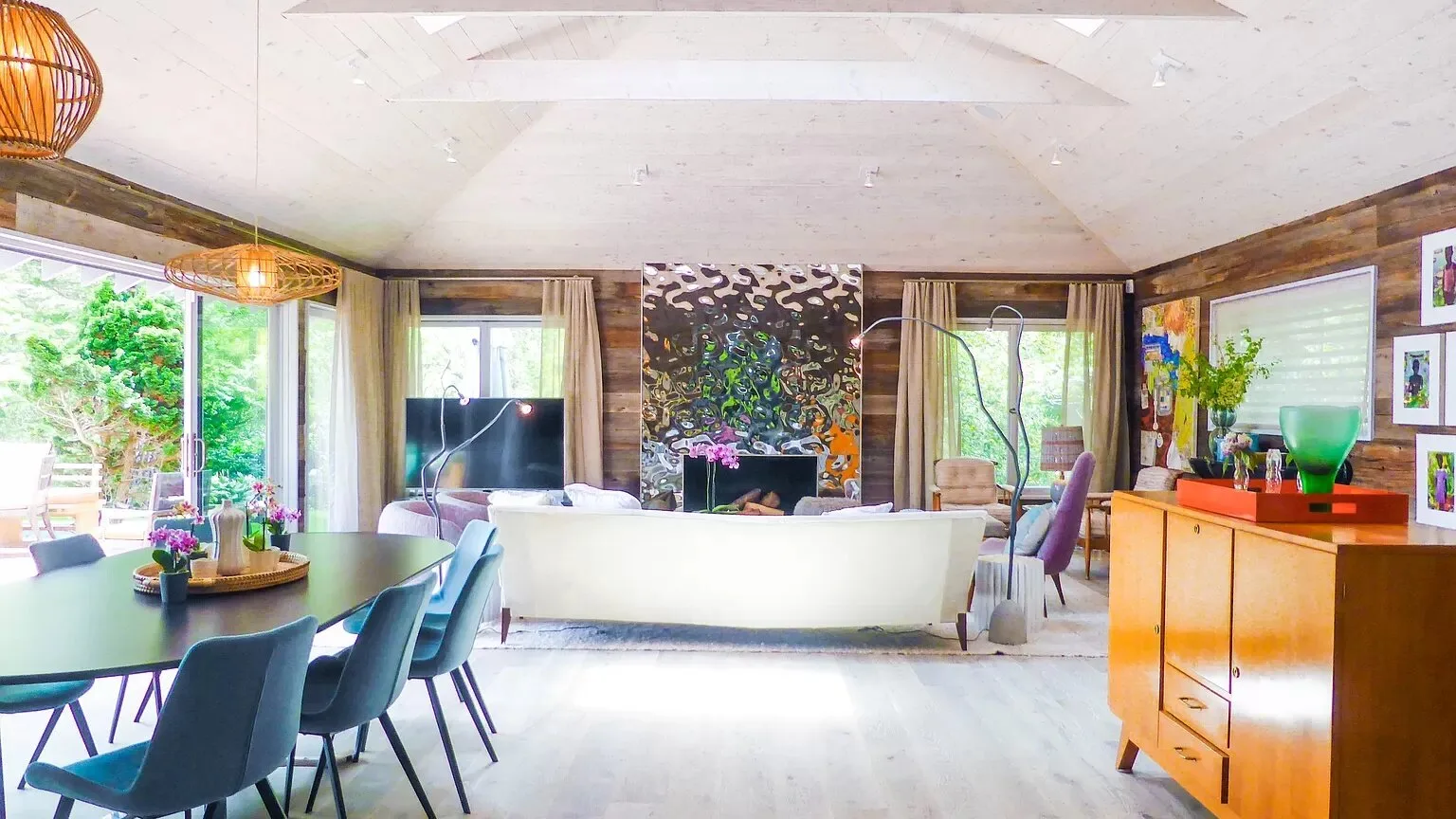 Una sala luminosa con zona de estar, mesa de comedor y grandes ventanales.