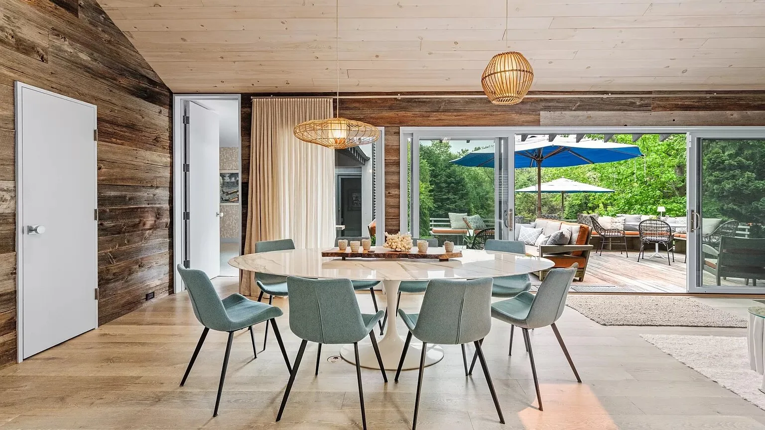 Comedor con una mesa redonda y sillas junto a puertas corredizas de vidrio que dan a un patio.