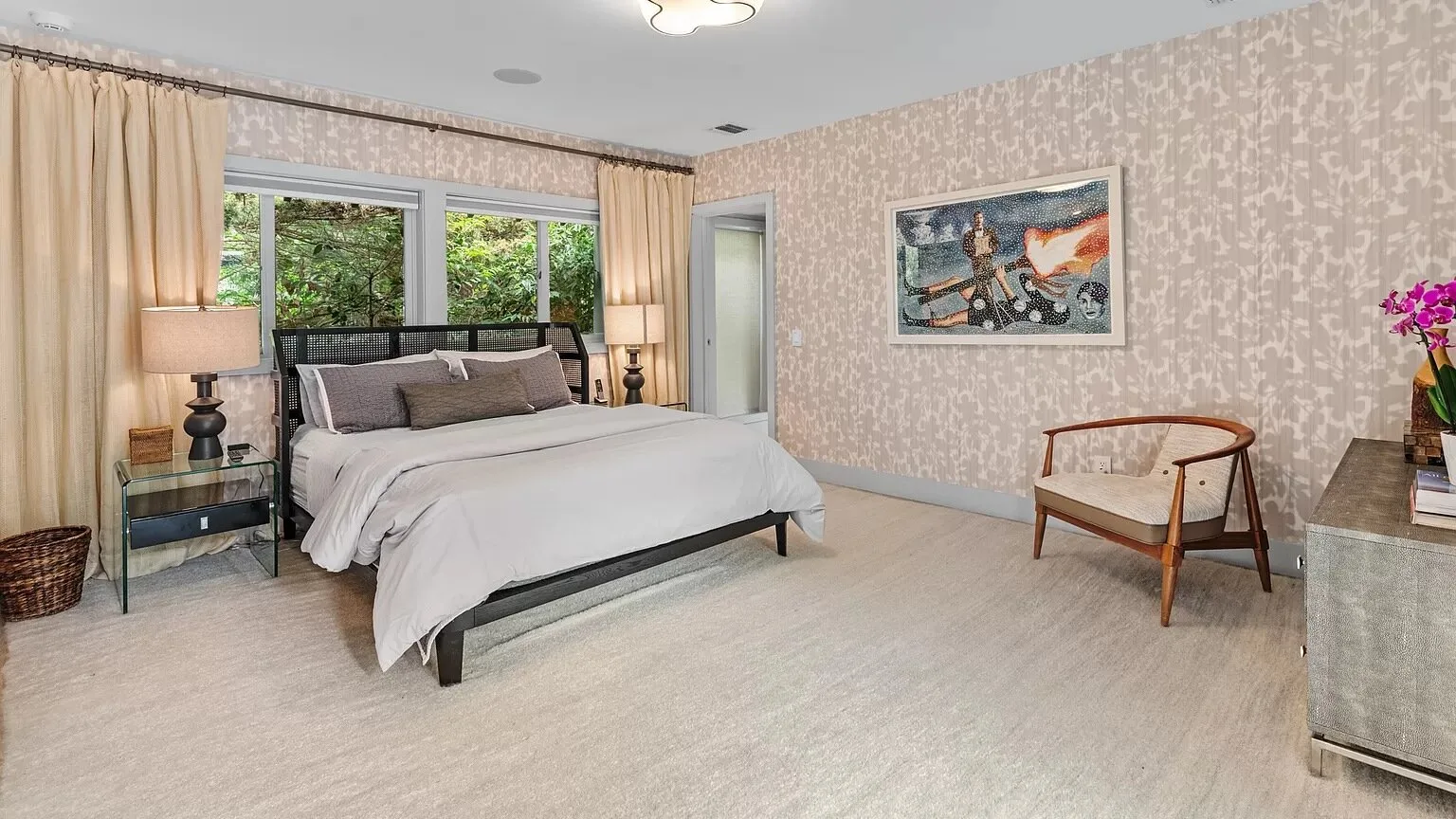 Un dormitorio con una cama, ventanas con cortinas y una silla.