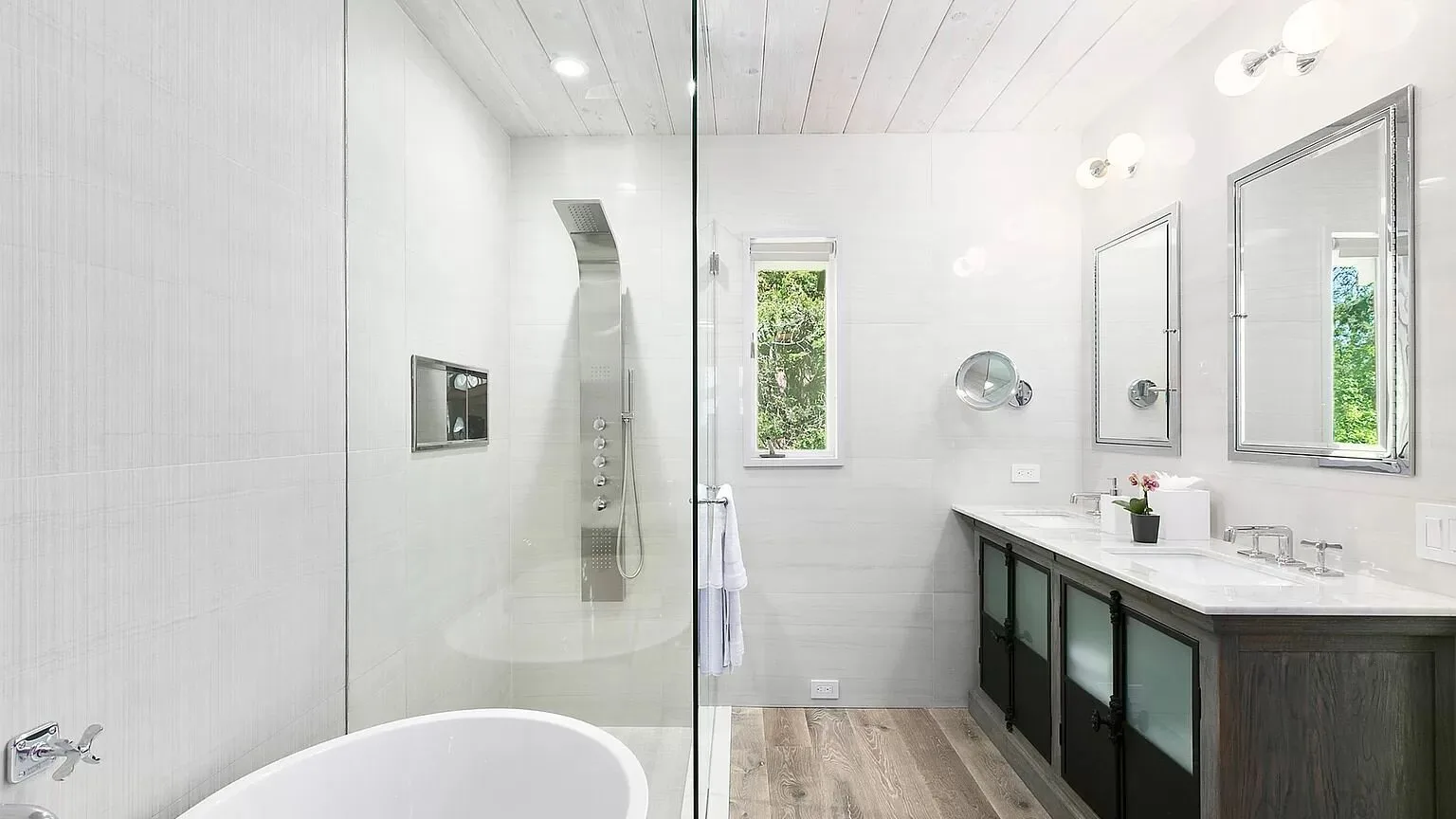 Un baño luminoso con una ducha de vidrio y un tocador largo.