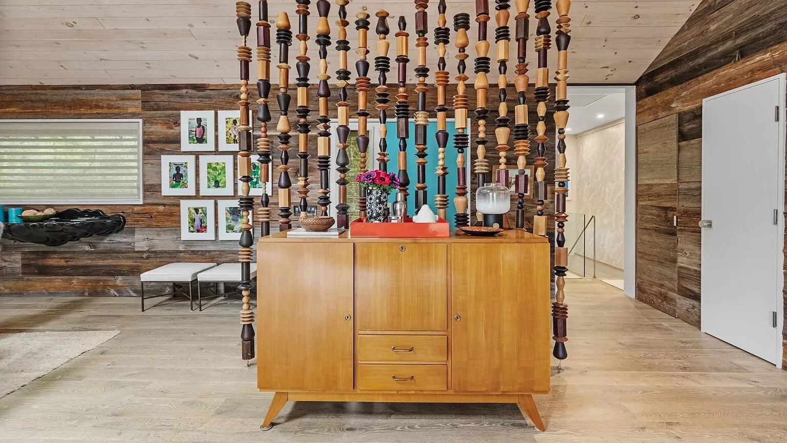Una habitación revestida de madera tiene un aparador bajo un separador colgante de madera.