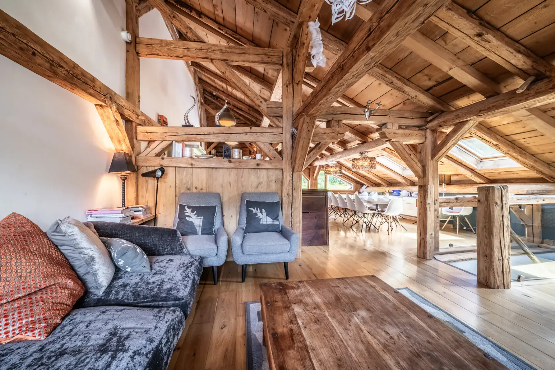 A living area with seating and a wooden table beneath exposed timber beams.