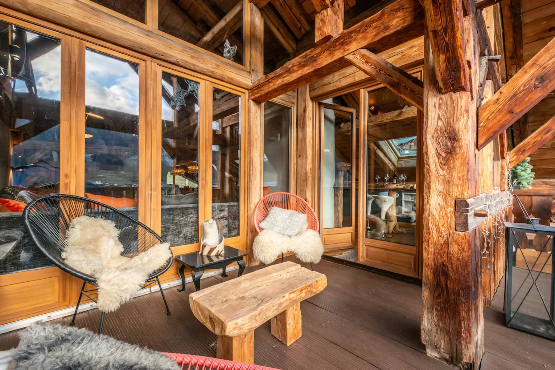 A timber-framed terrace with seating beside large glass doors.