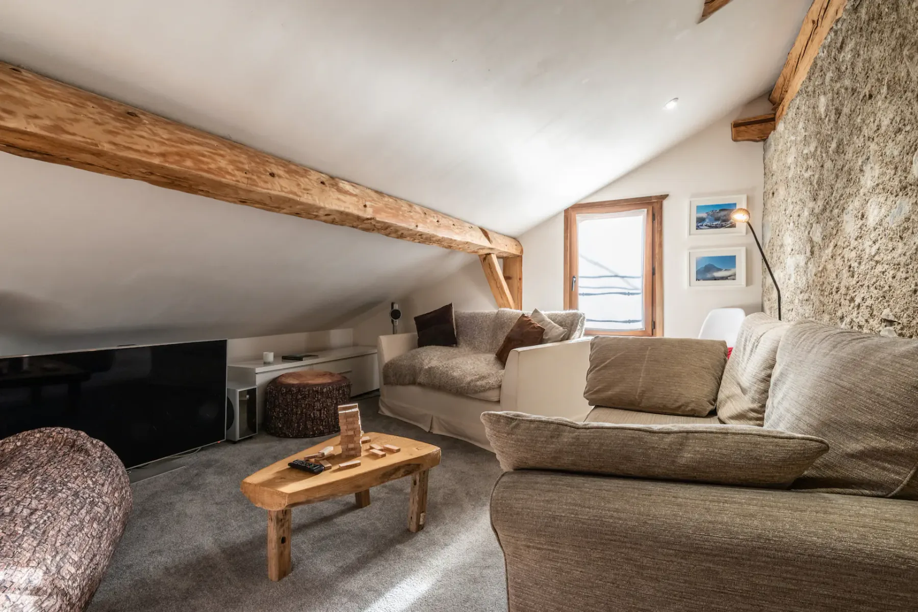 A cozy lounge with seating, a television, and a low wooden coffee table.