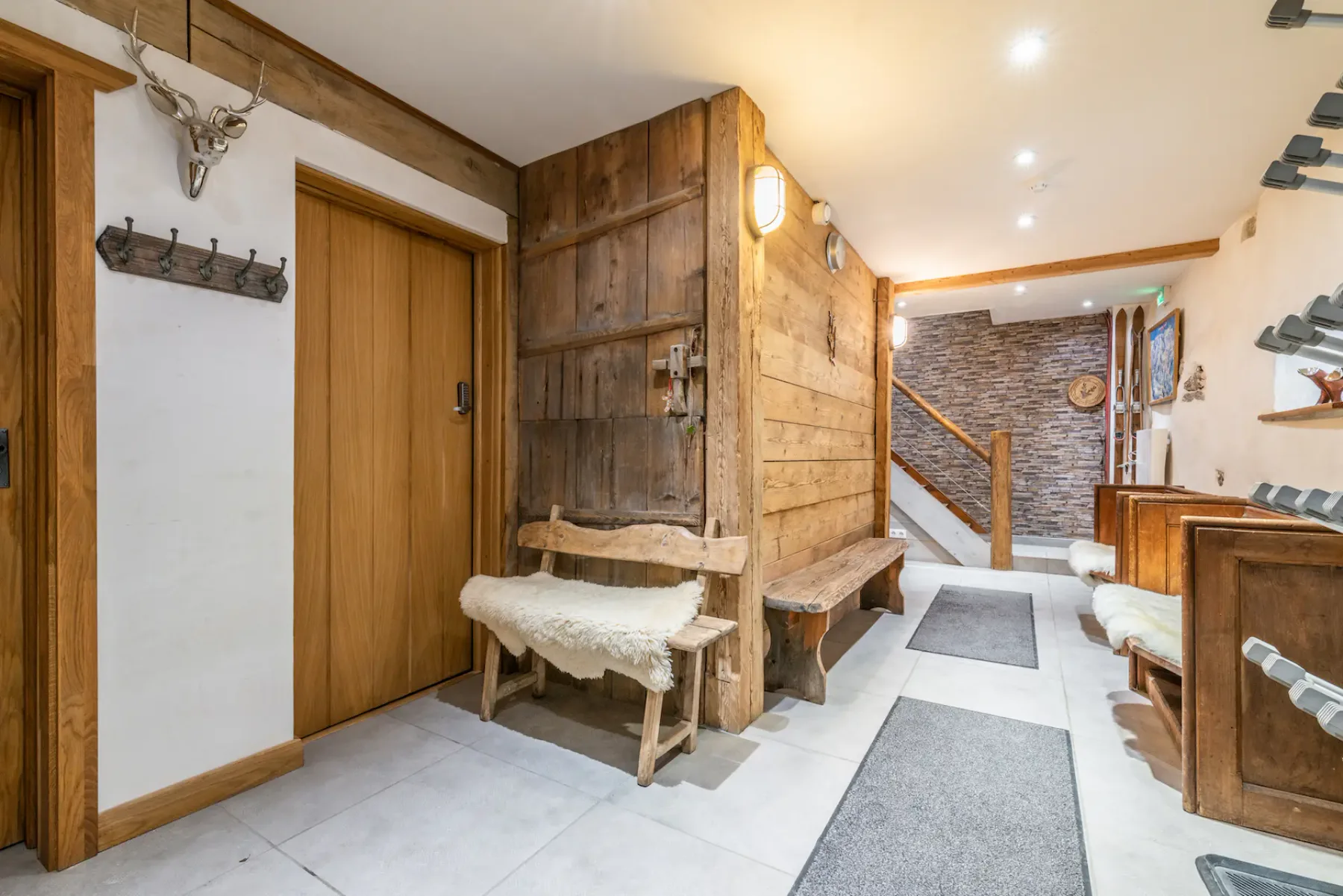 A wood-paneled entry hall with benches and a staircase at the back.