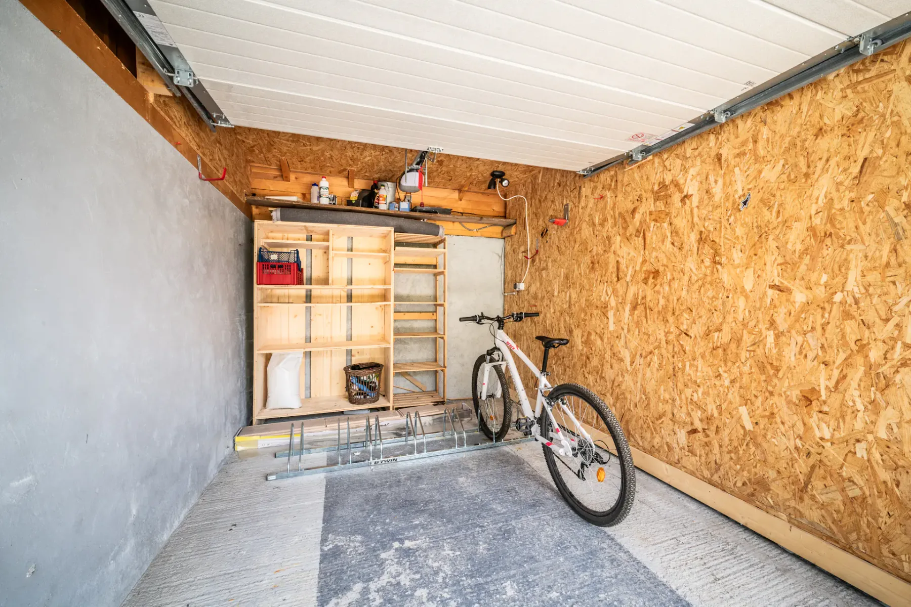 A garage with a bicycle and wooden storage shelves.