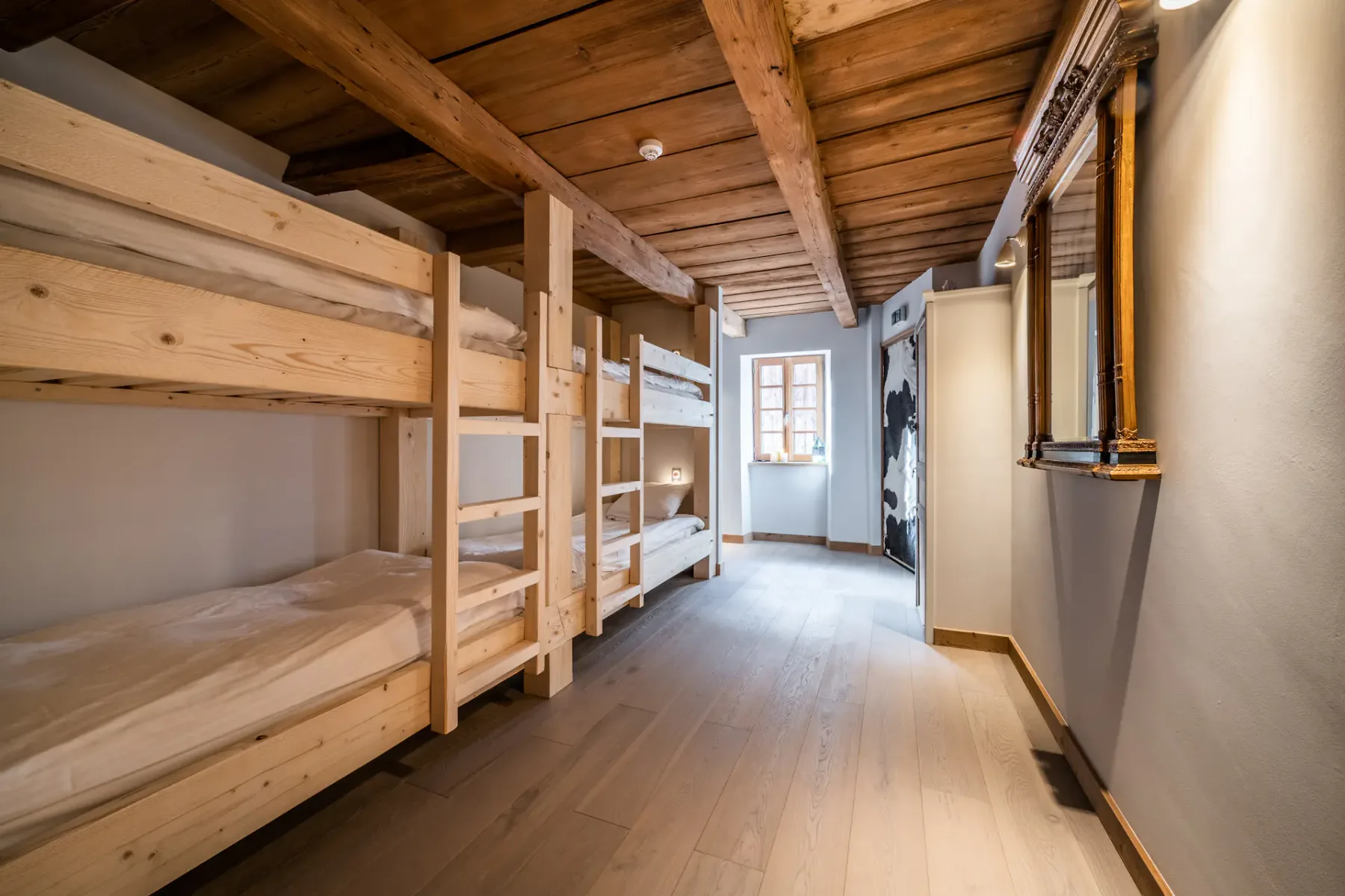 A bedroom with wooden bunk beds and a window at the far end.
