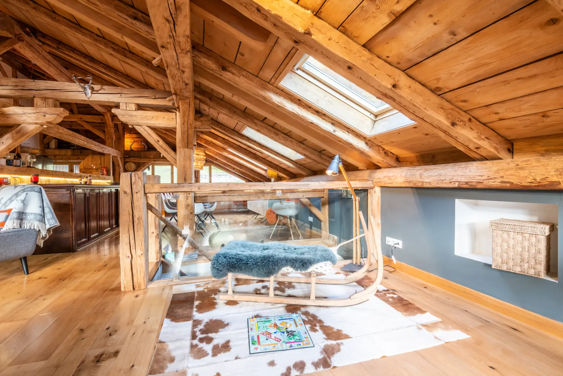 A wood-paneled loft seating area with skylights and a glass railing.