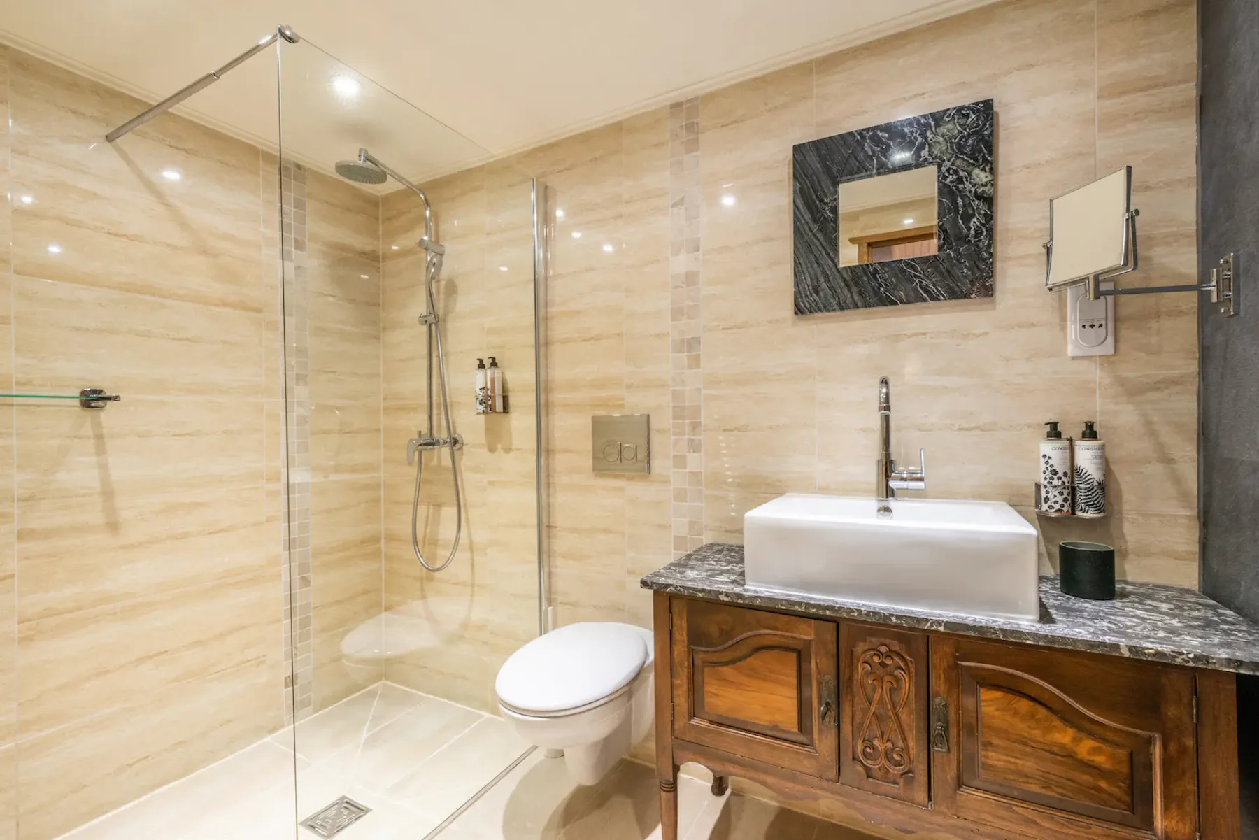 A bathroom with a glass shower, toilet, and wooden vanity.