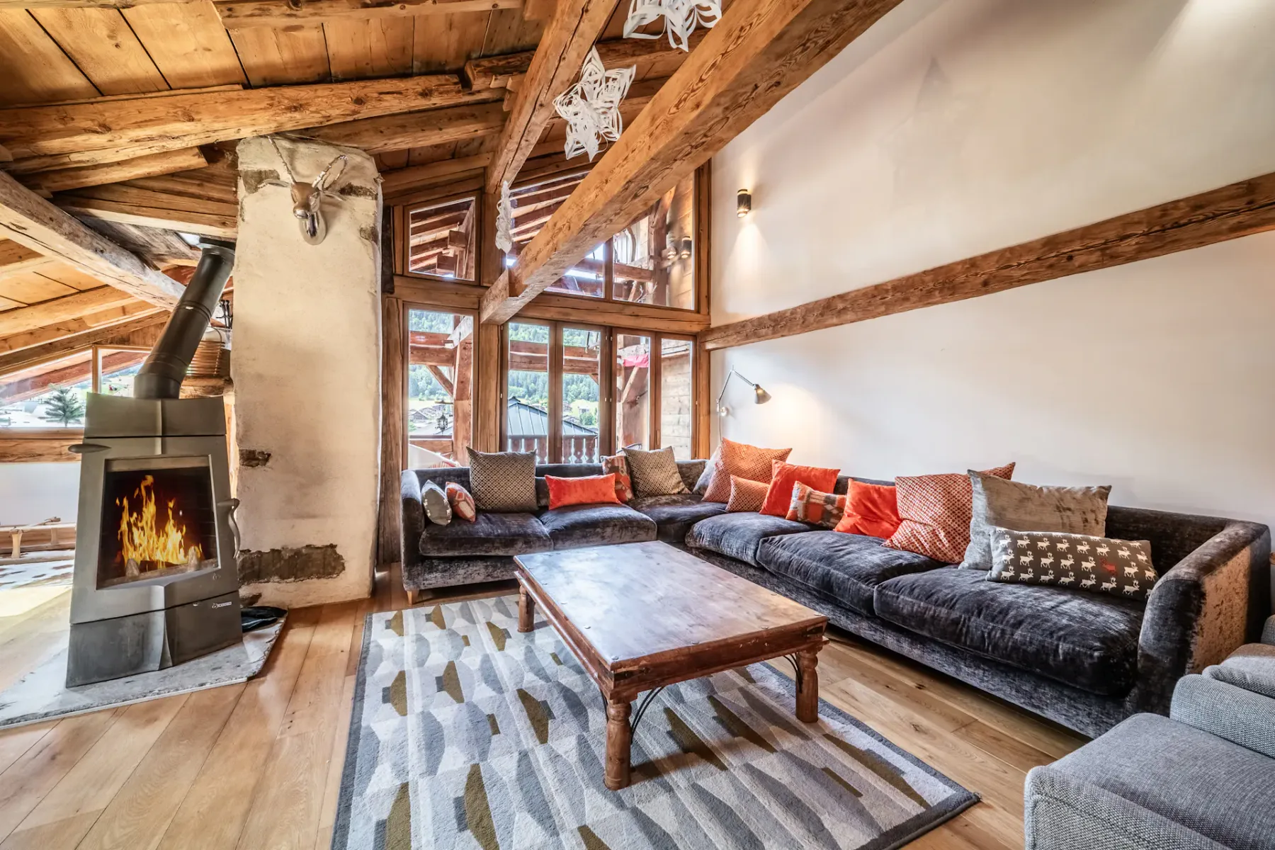 A spacious living room with seating, a wooden coffee table, and a lit fireplace.