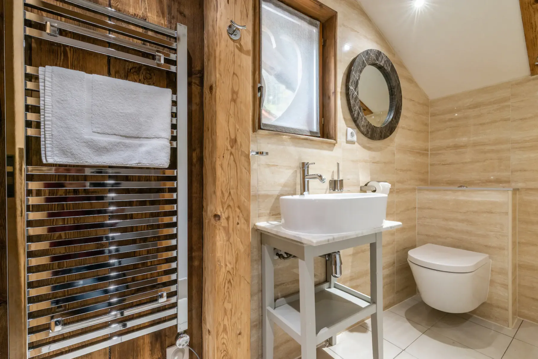 A bathroom with a sink, wall-mounted toilet, and heated towel rail.