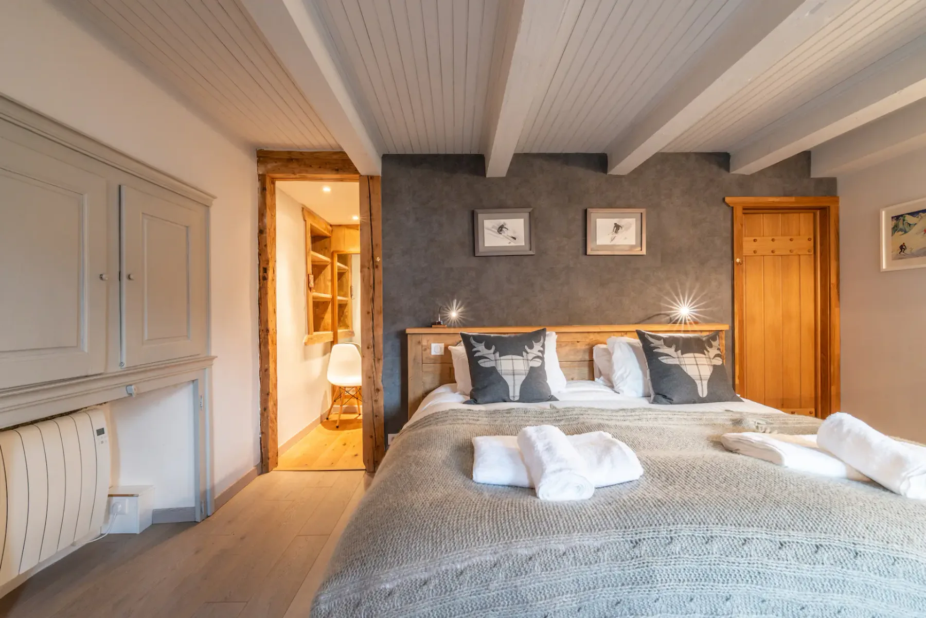A bedroom with a large bed, gray bedding, and a wooden headboard.