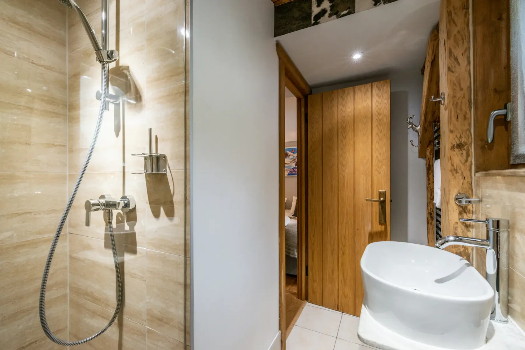 A bathroom with a glass shower, sink, and wooden doors.