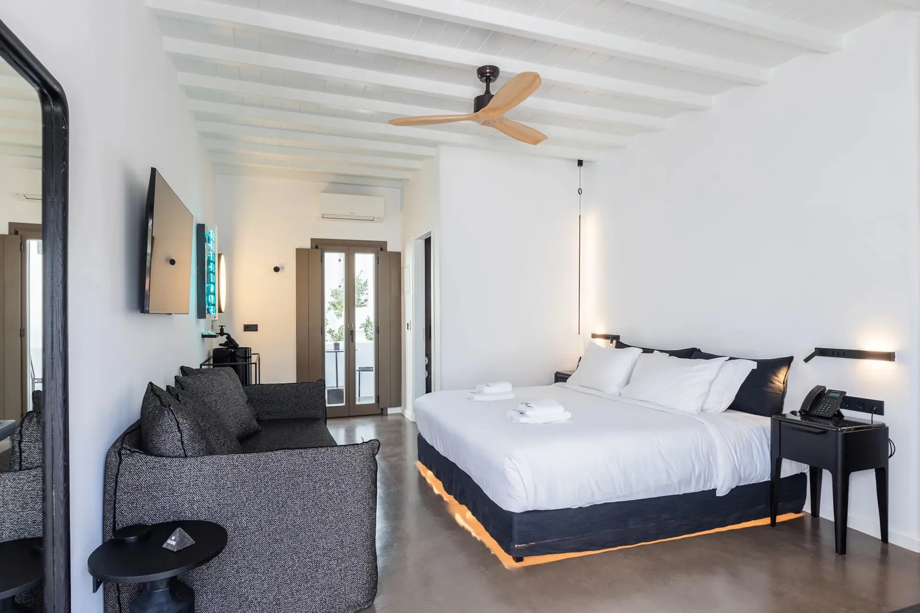 Un dormitorio luminoso con una cama amplia, asientos y un ventilador de techo.