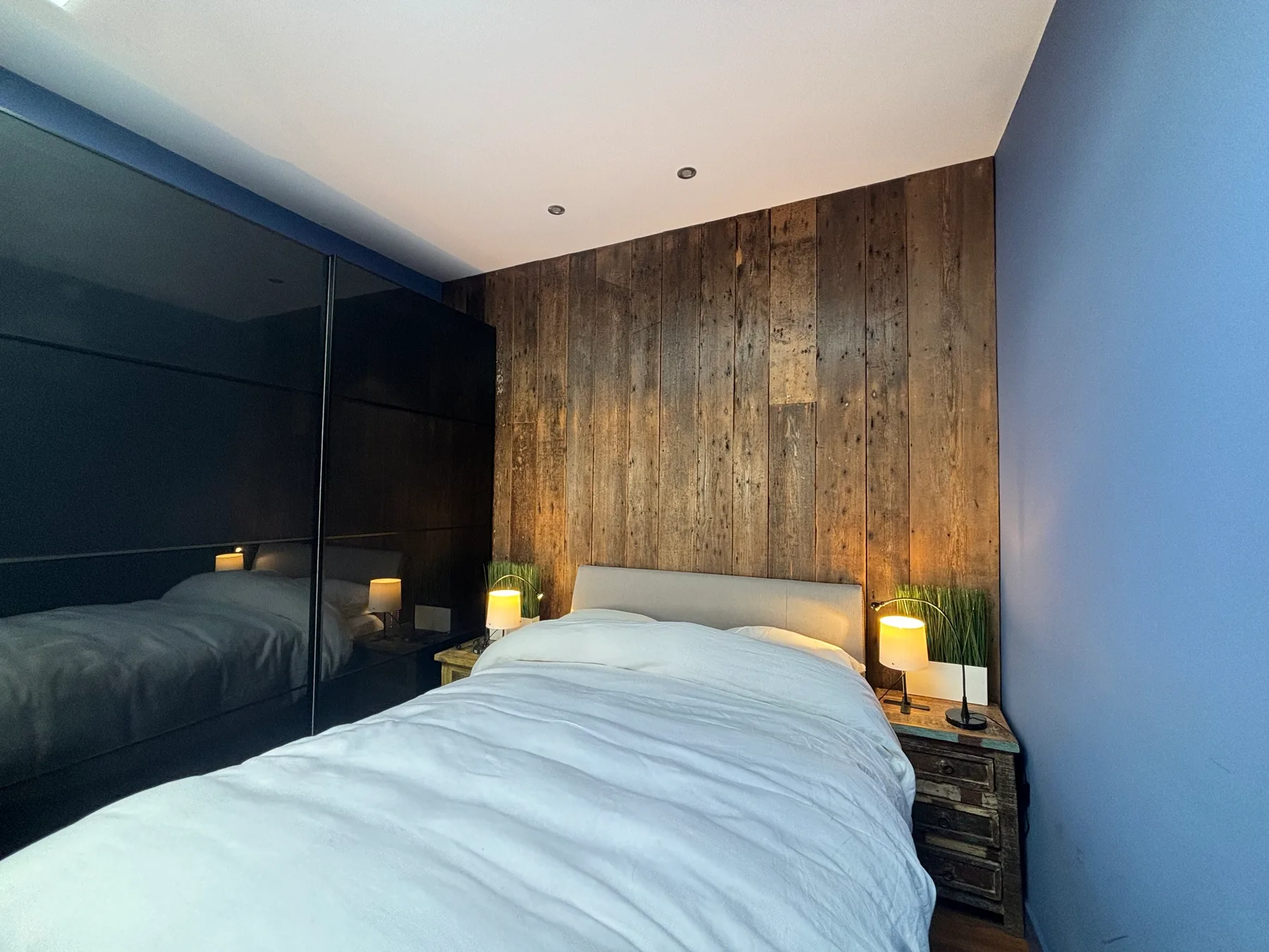 A bedroom with a bed against a wood-paneled wall and bedside lamps.