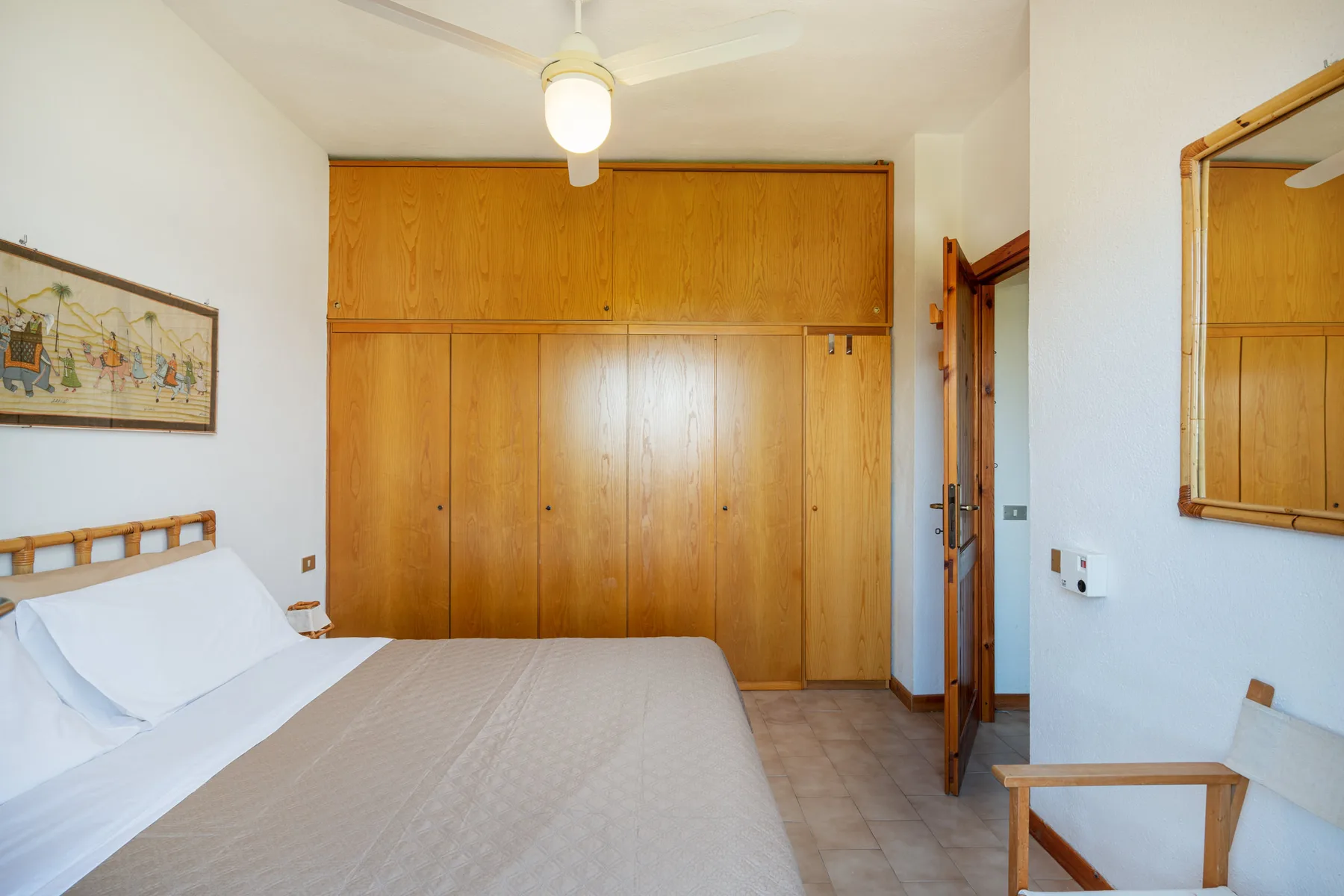 A bedroom with a bed beside a large wooden wardrobe.