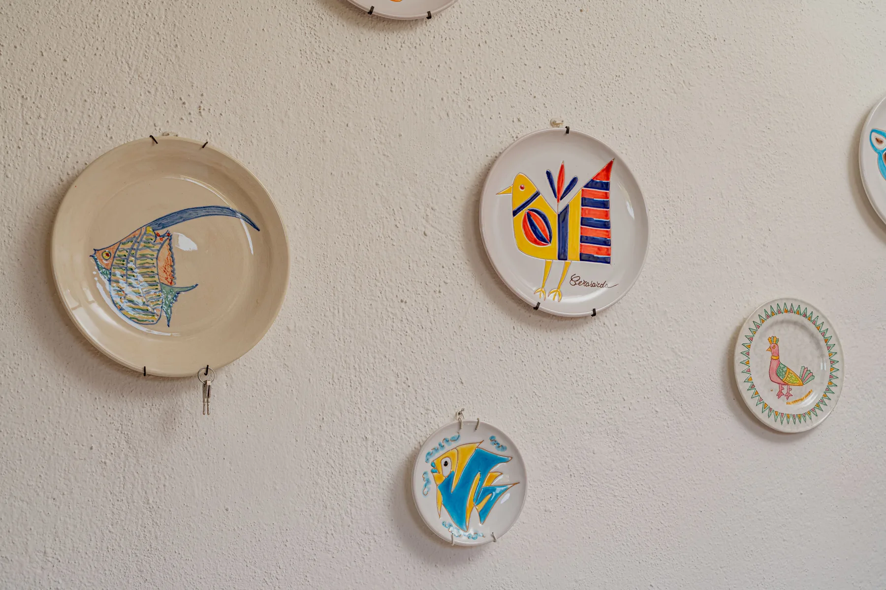A wall display of decorative plates, including colorful painted designs.