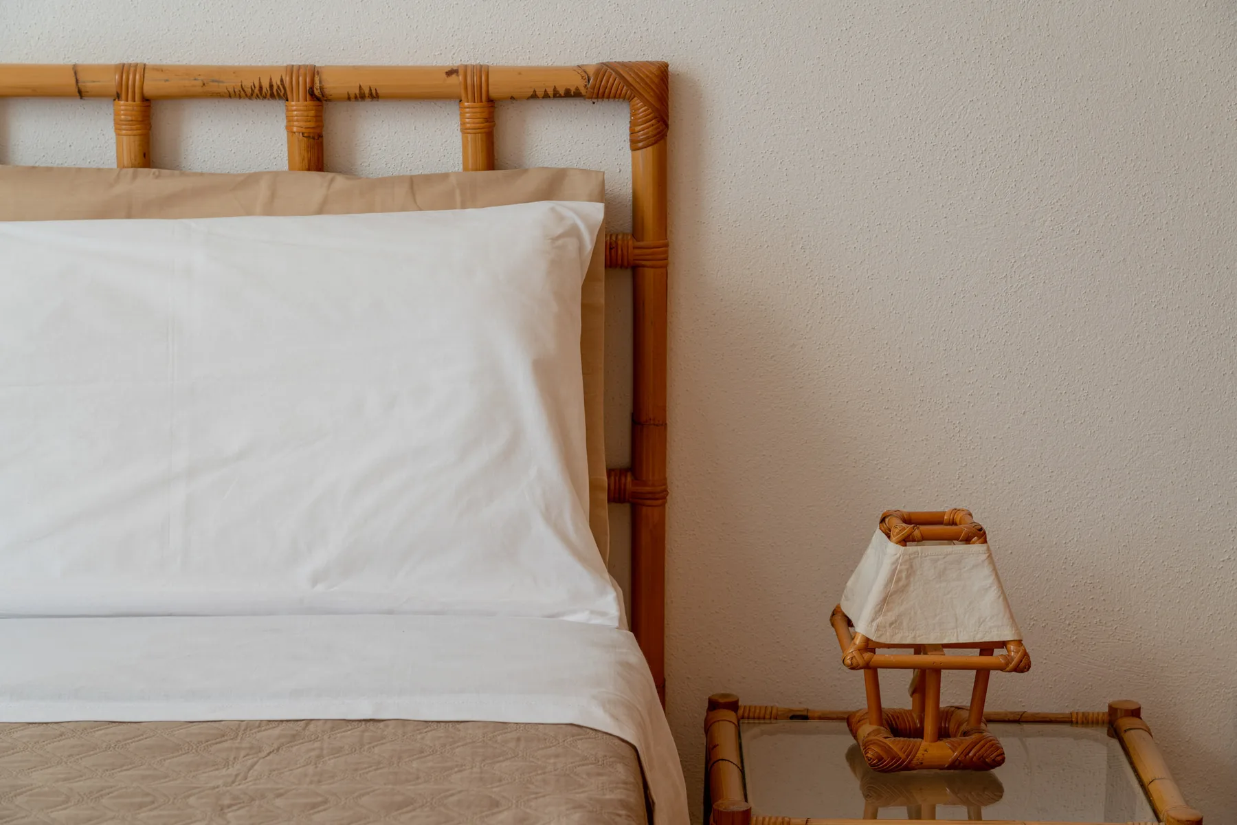 A bedroom scene with white bedding and a bedside lamp.