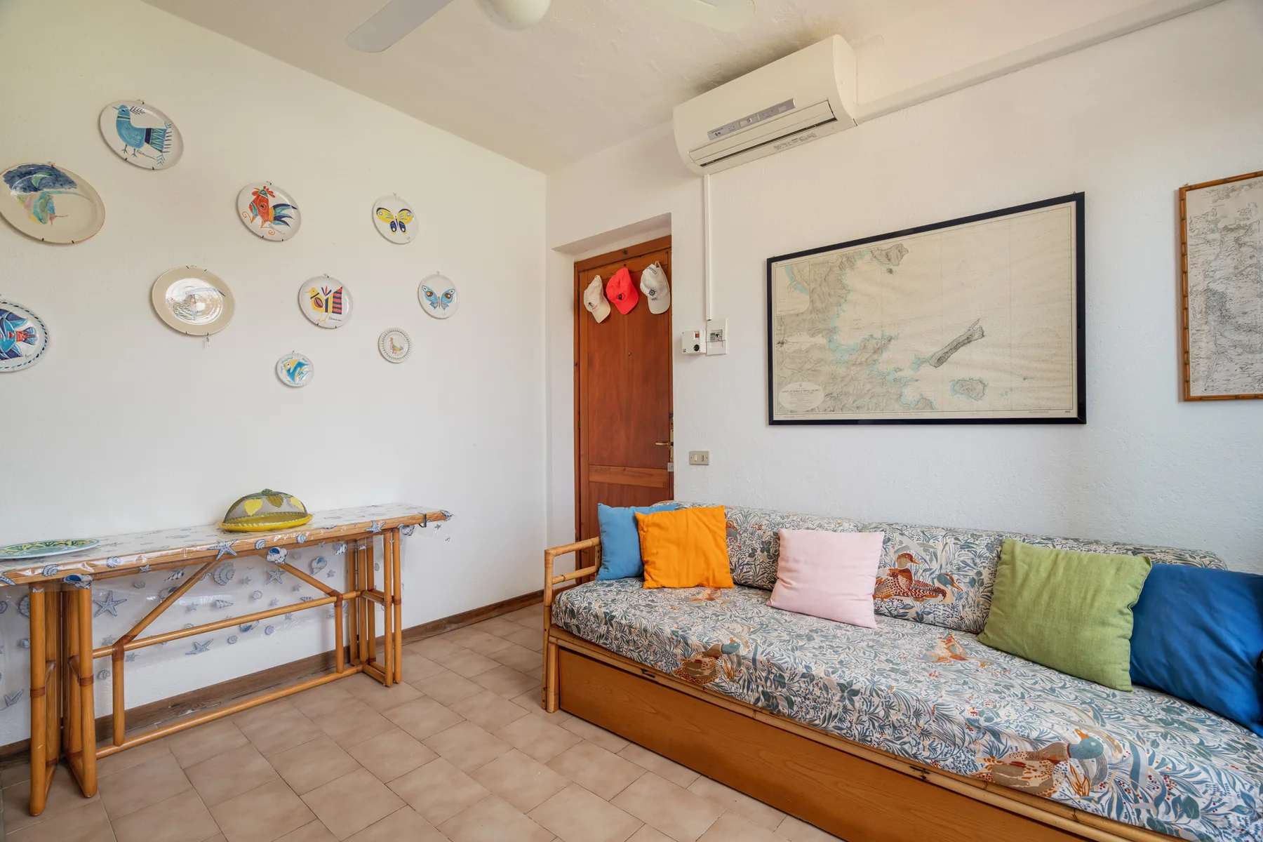 A living room with a patterned daybed and colorful cushions.