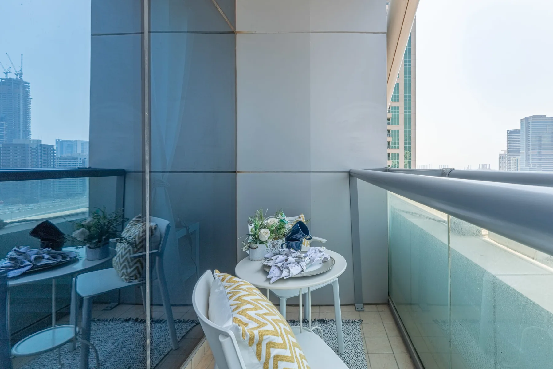 Zona de estar en un balcón con una mesa pequeña y vistas a la ciudad.
