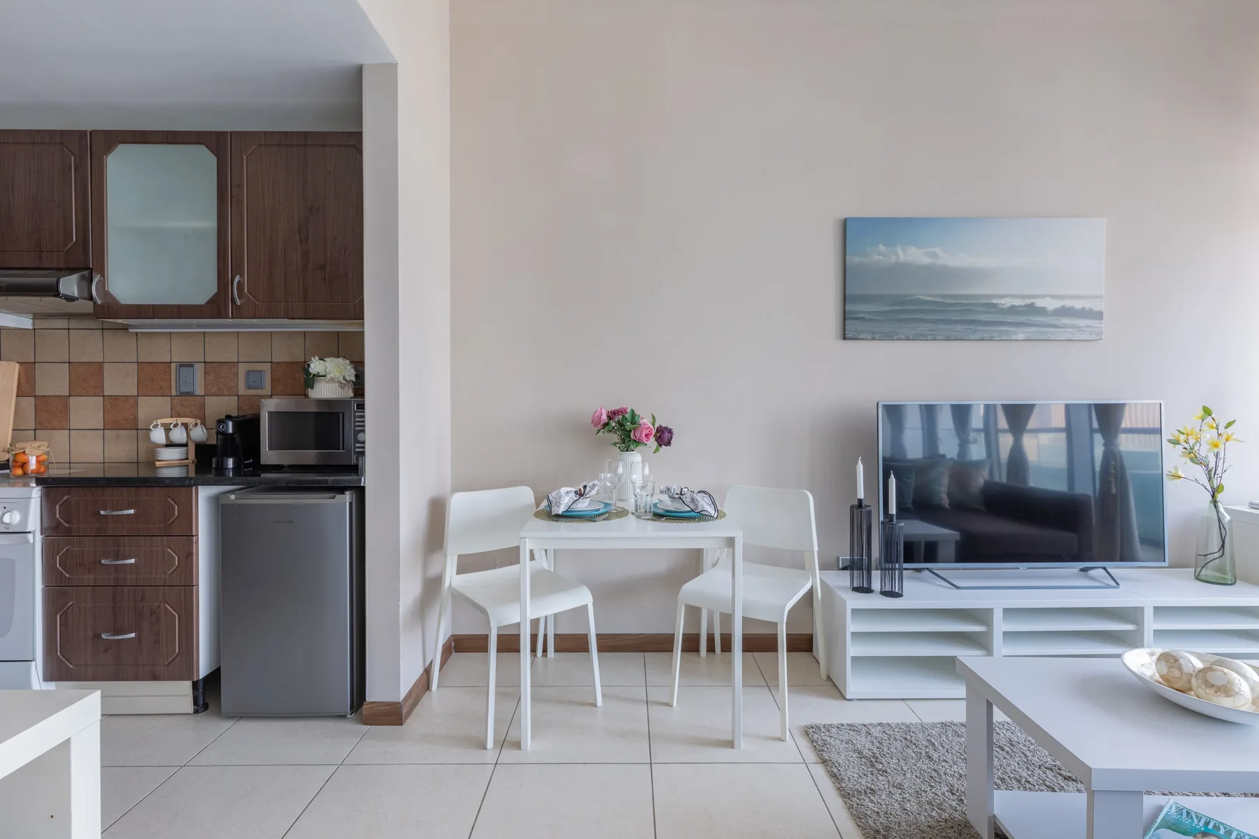 Un comedor con una mesa pequeña y sillas está junto a una cocina compacta.