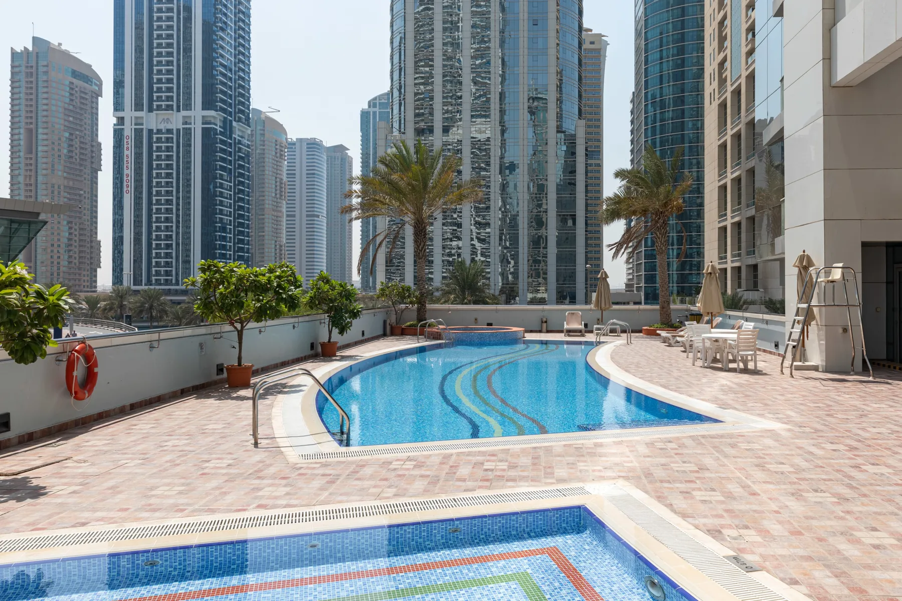 Una piscina al aire libre y una piscina poco profunda están rodeadas de altos edificios urbanos.