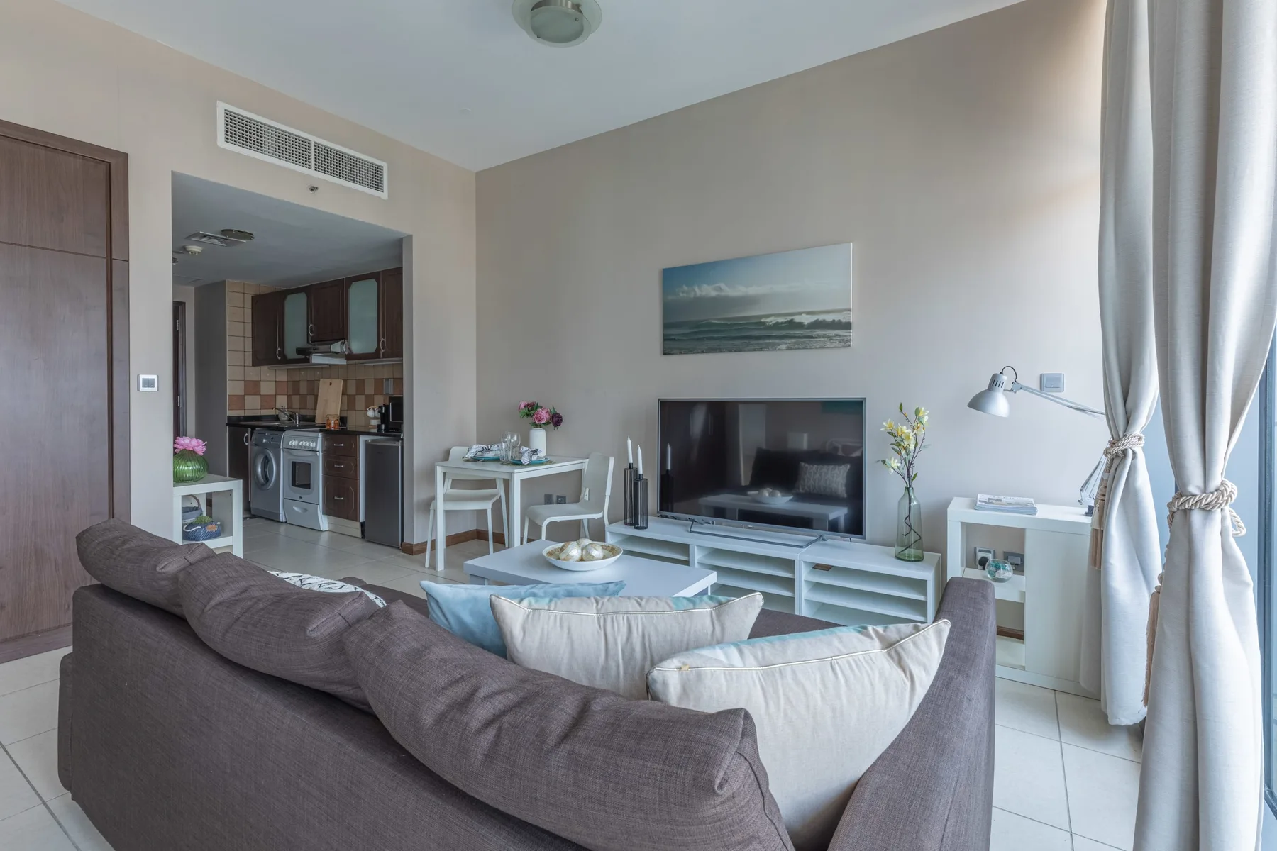 Una sala de estar con asientos, un televisor y un comedor.