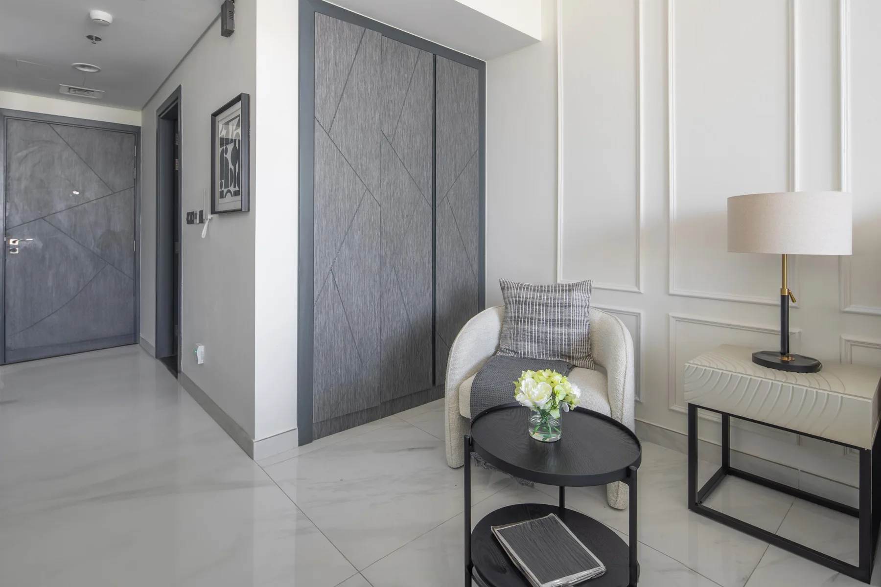 Una zona de estar con sillón, mesa de centro y lámpara.