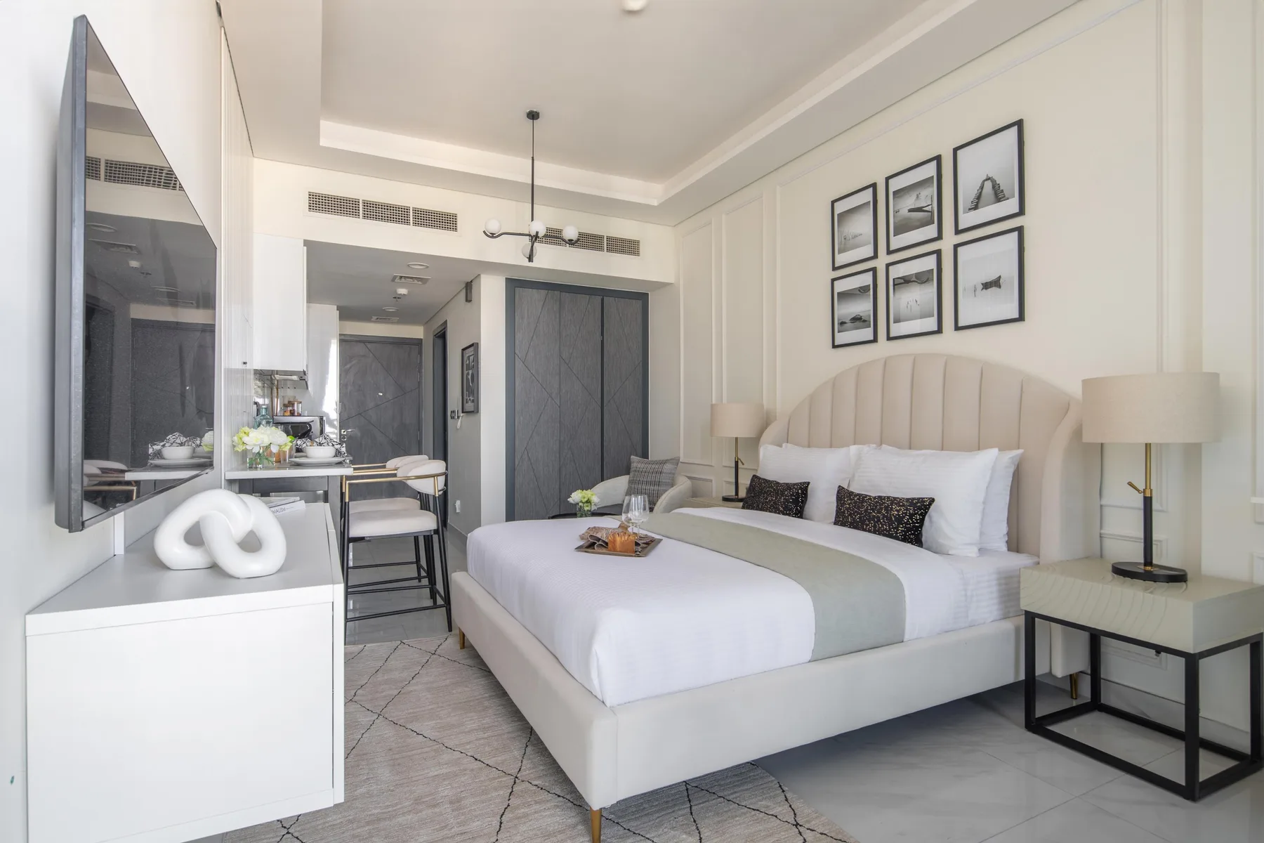 A bright bedroom with a large bed, bedside tables, and framed wall art.