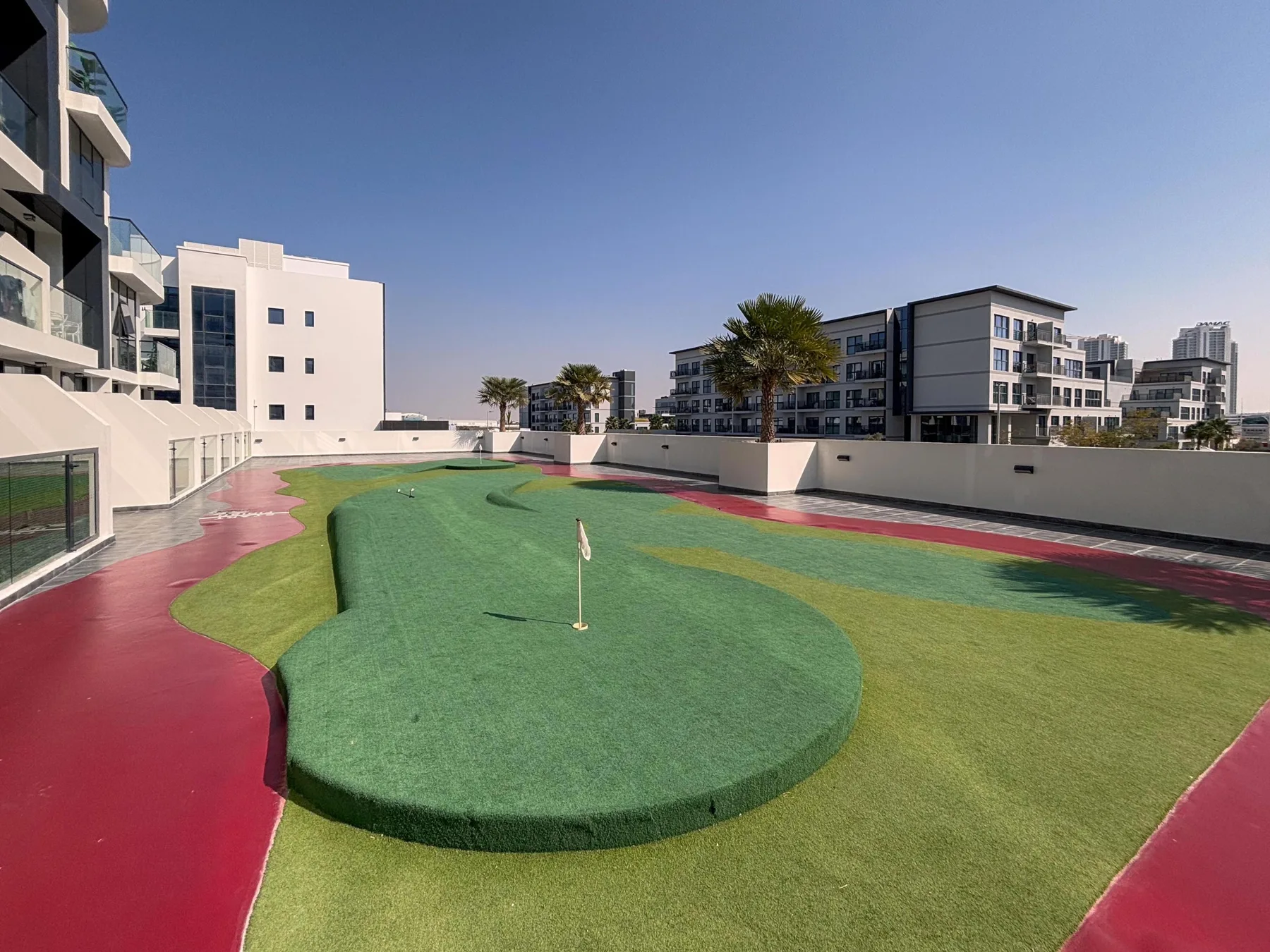 Una zona de minigolf al aire libre tiene una superficie elevada para jugar rodeada de caminos de colores.
