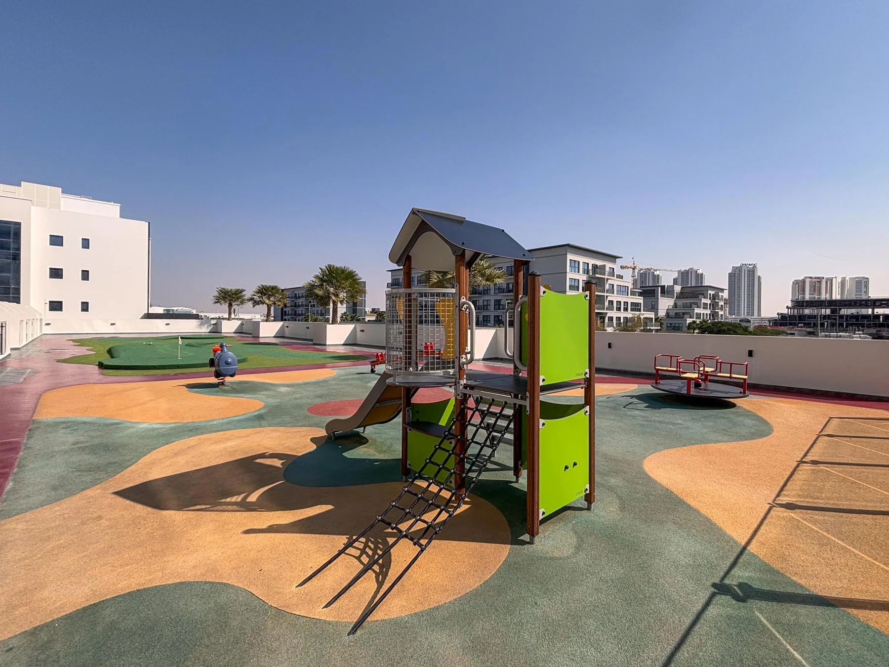 Un parque infantil en la azotea con una estructura de escalada colorida y una zona de juego abierta.