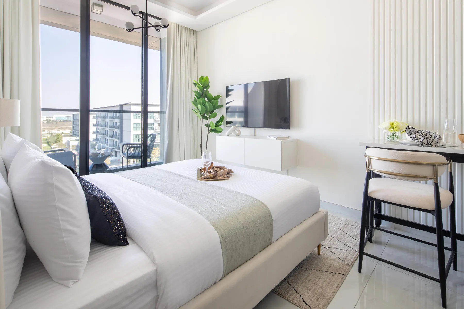 Un dormitorio luminoso con una cama bien hecha junto a grandes ventanales.