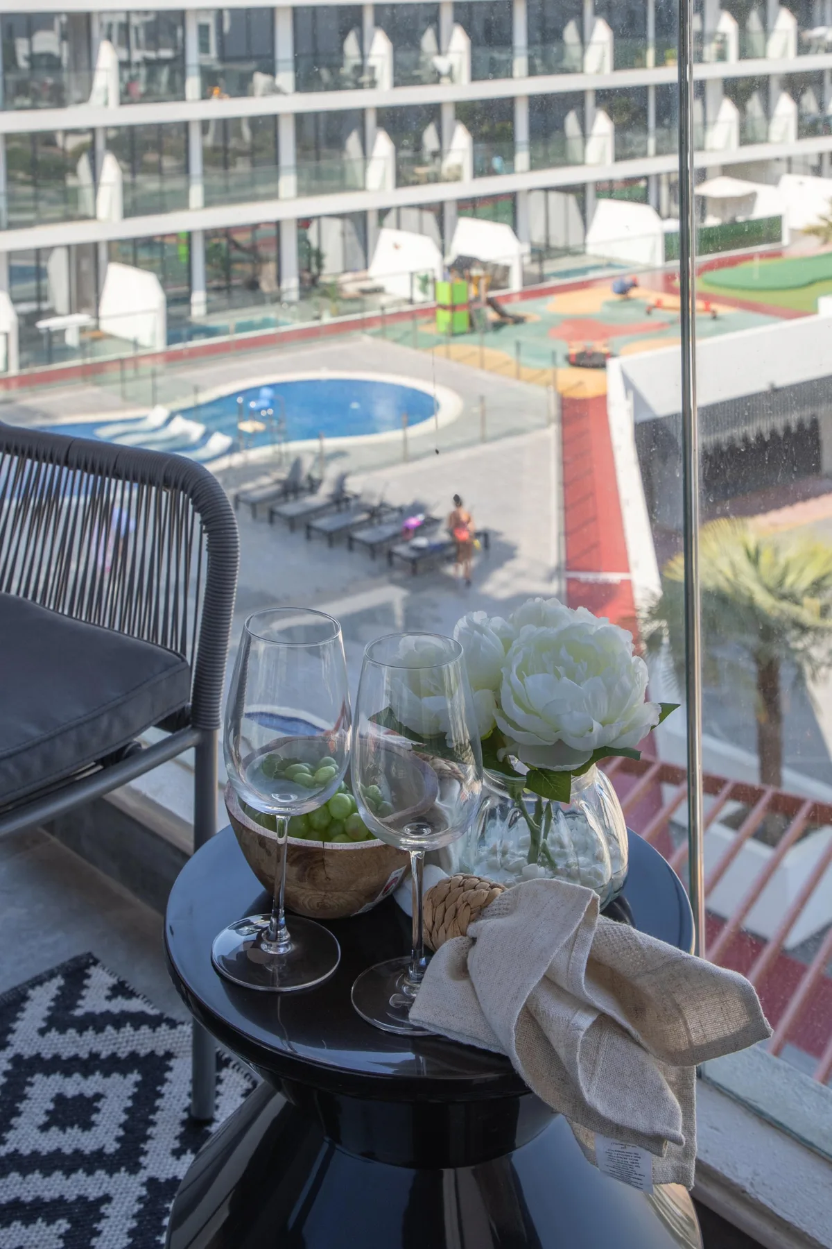 Una zona de estar en un balcón da a una piscina y áreas recreativas al aire libre.