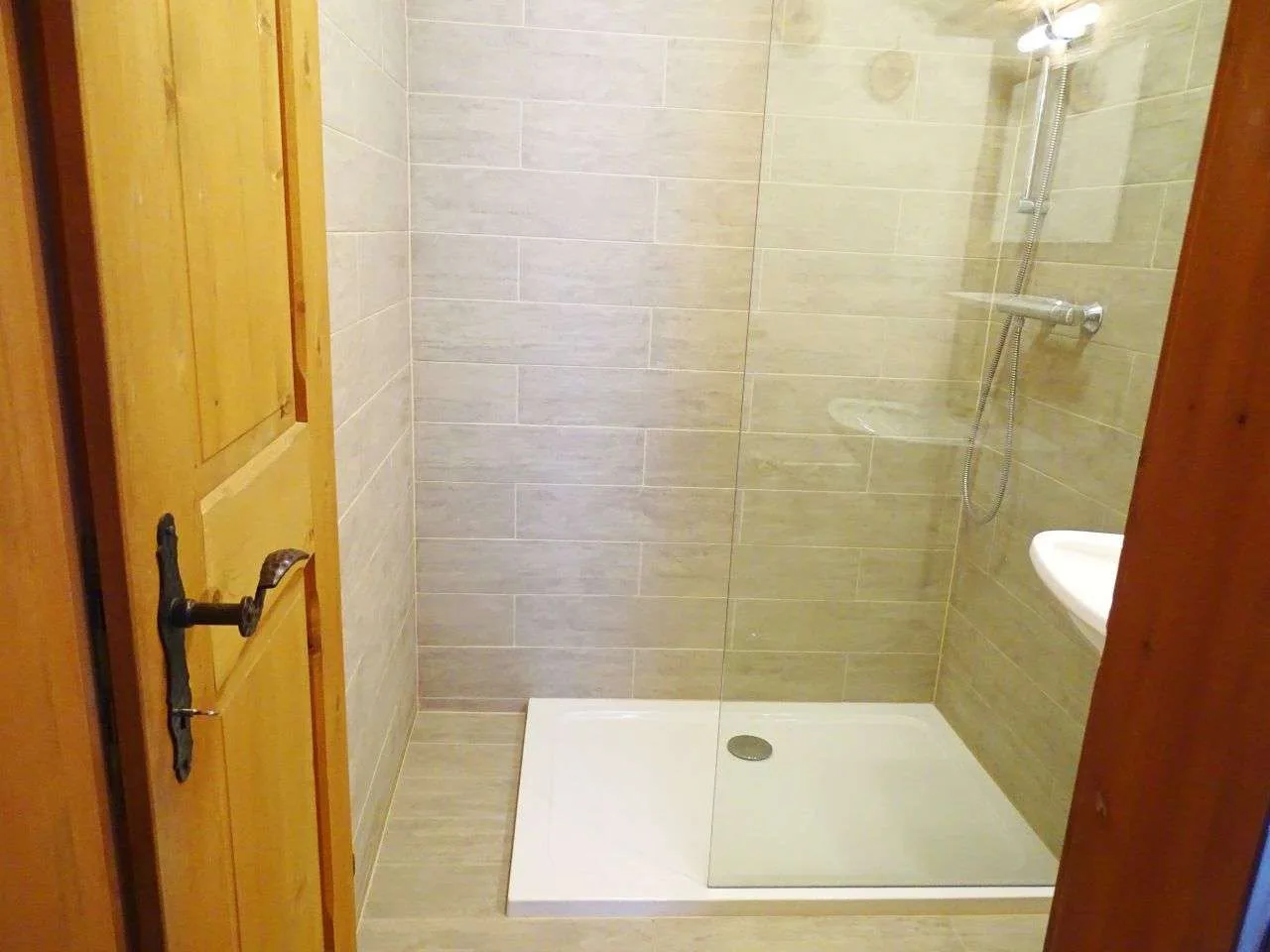 A tiled bathroom shower with a glass screen and white shower tray.
